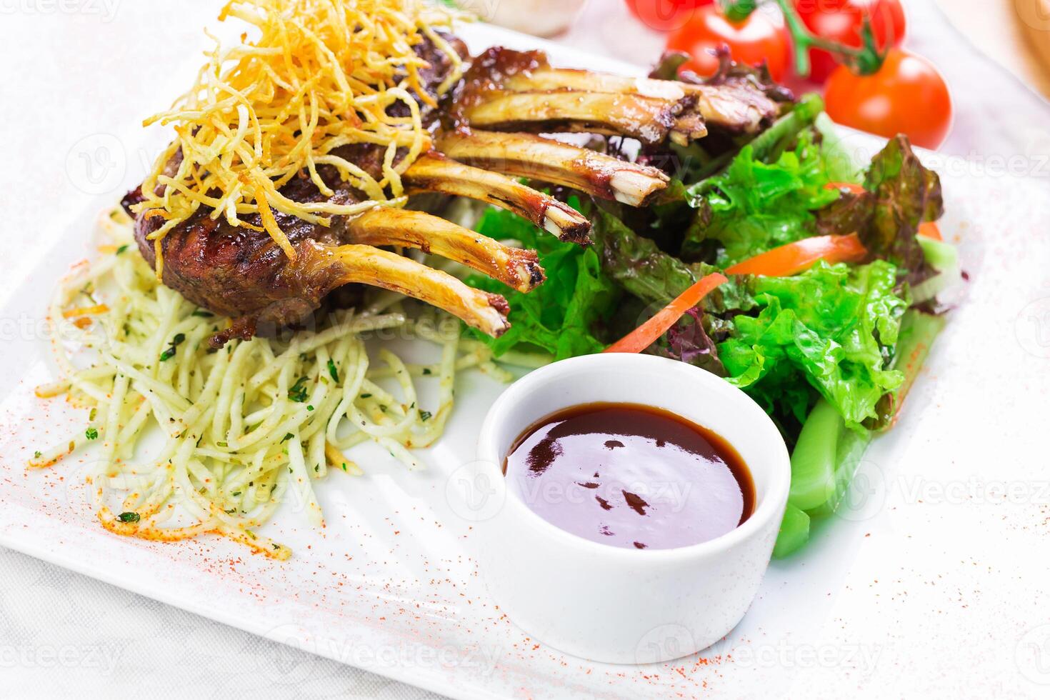 Delicious grilled lamb chops served with fresh salad and a flavorful sauce on a white plate photo