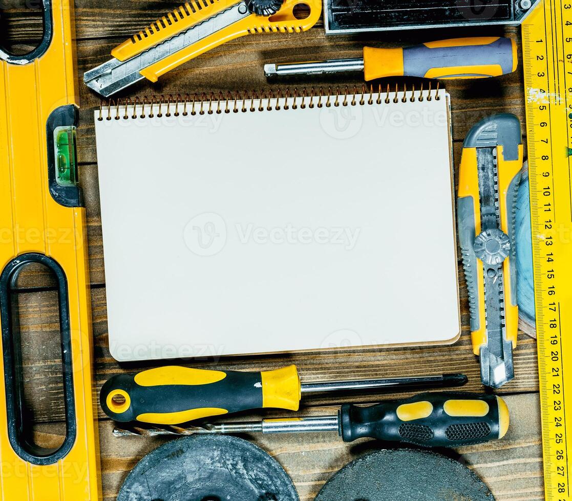 Tools and equipment arranged on a wooden surface with a blank notebook ready for notes and sketches during a DIY project photo
