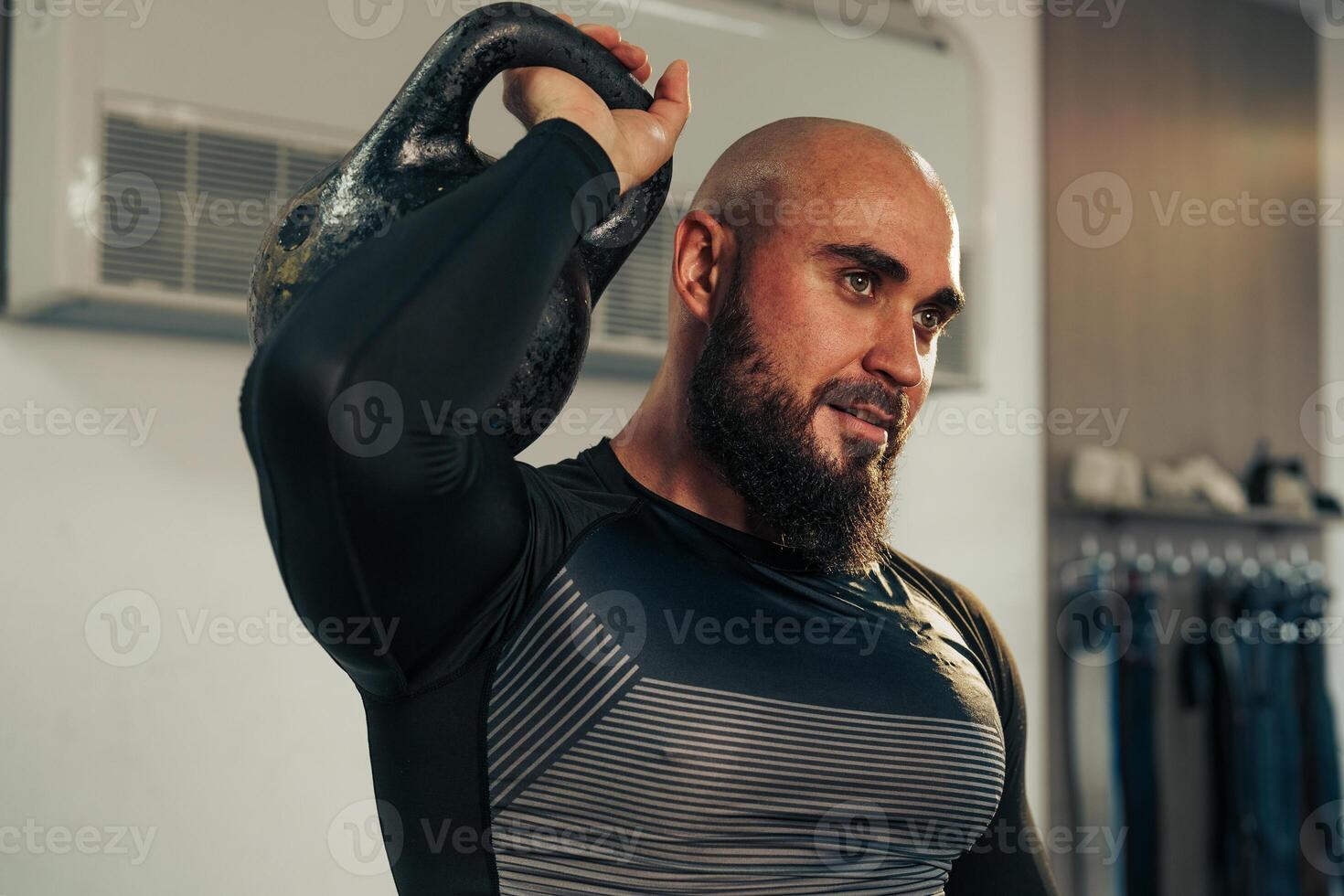 Man exercising with a kettlebell in a modern gym environment while focused on his workout routine photo