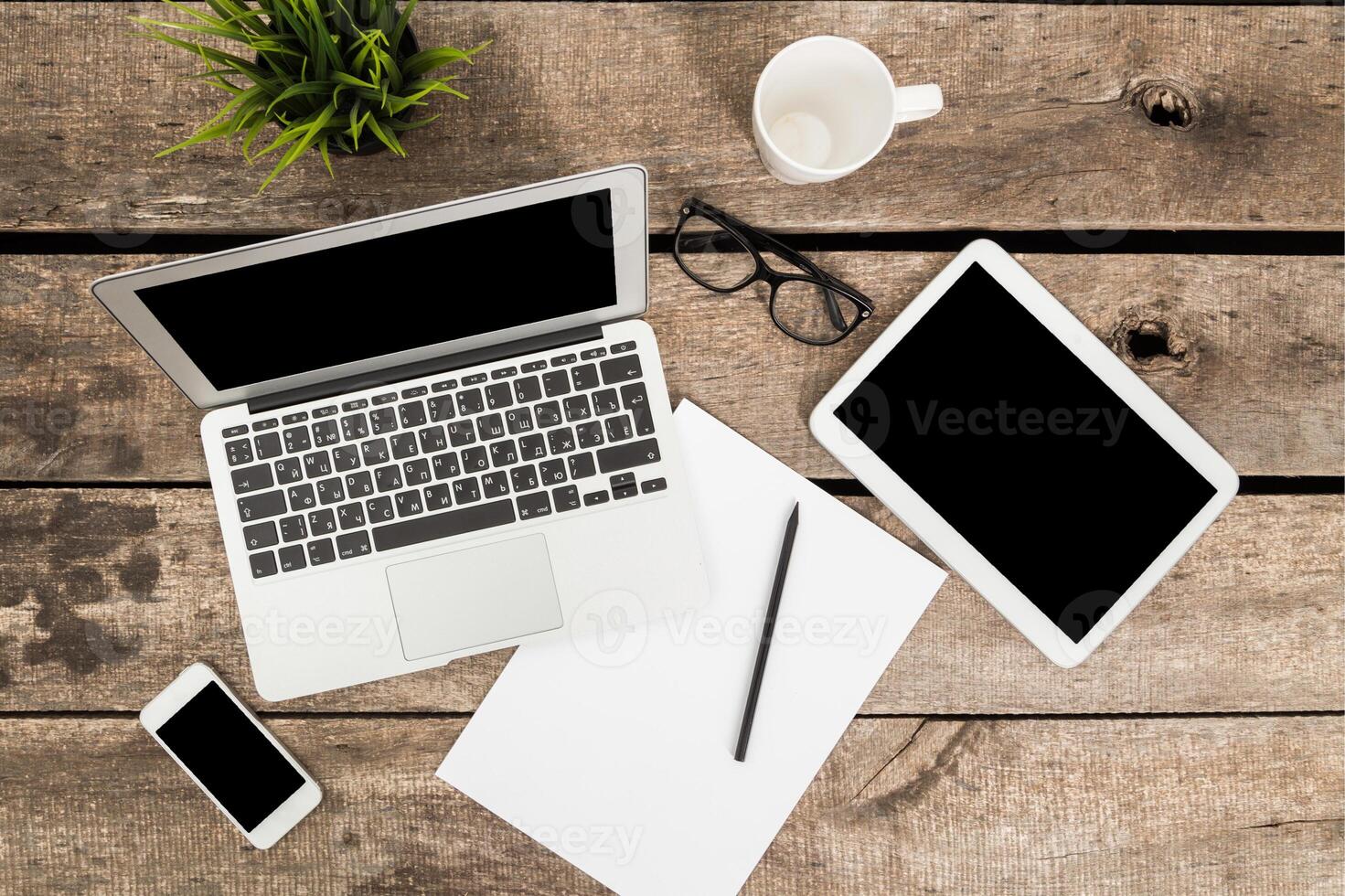 Office workspace with laptop, tablet, smartphone, and stationery arranged on wooden table photo