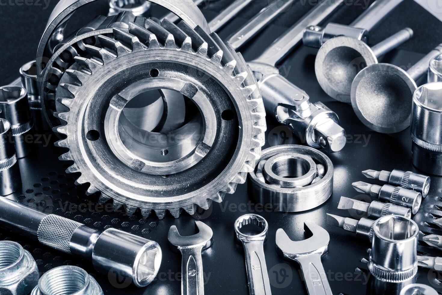 Collection of metallic tools and gears arranged neatly on a black surface in a workshop setting photo