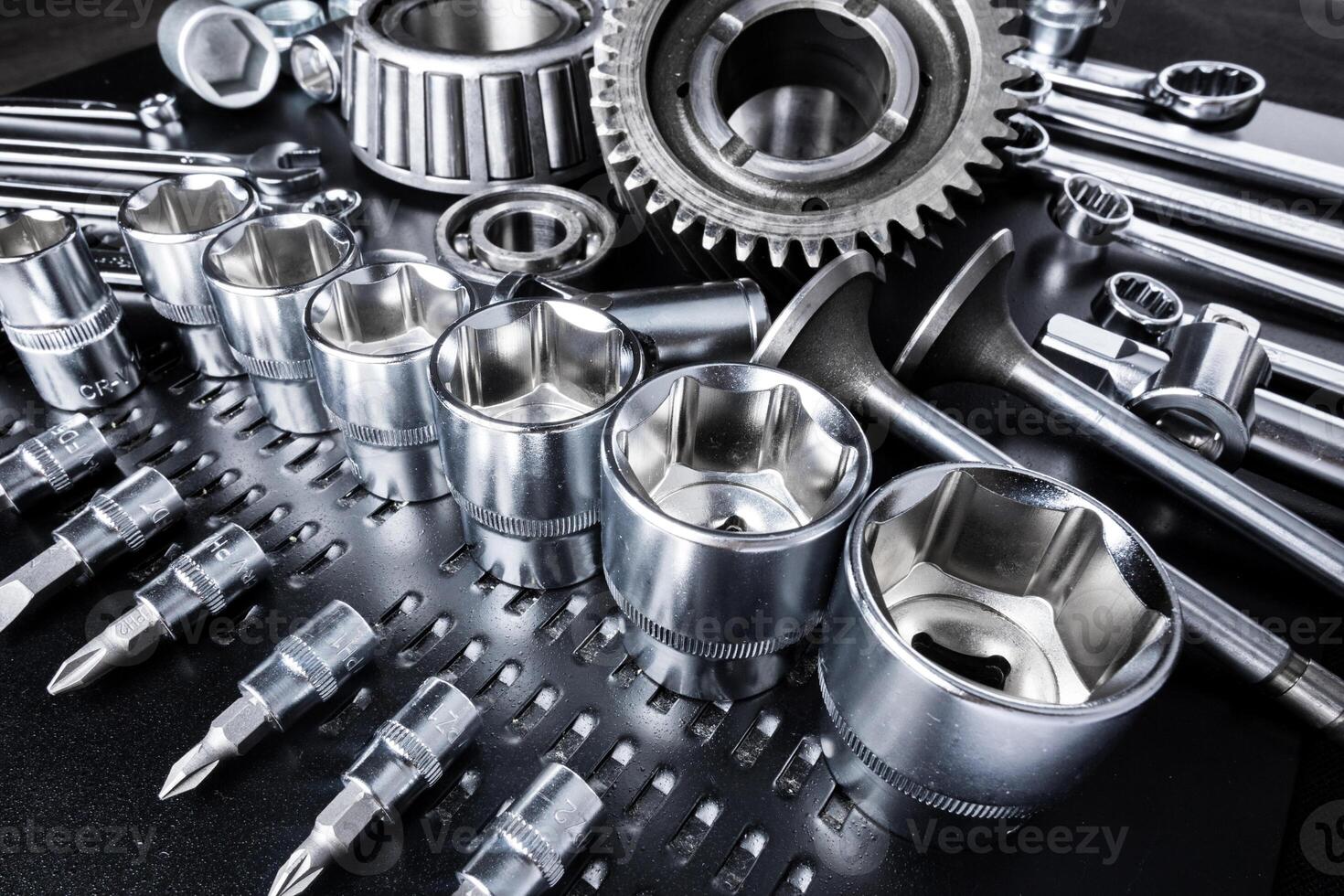 Collection of chrome tools arranged neatly on a black workbench in a well-lit garage setting photo