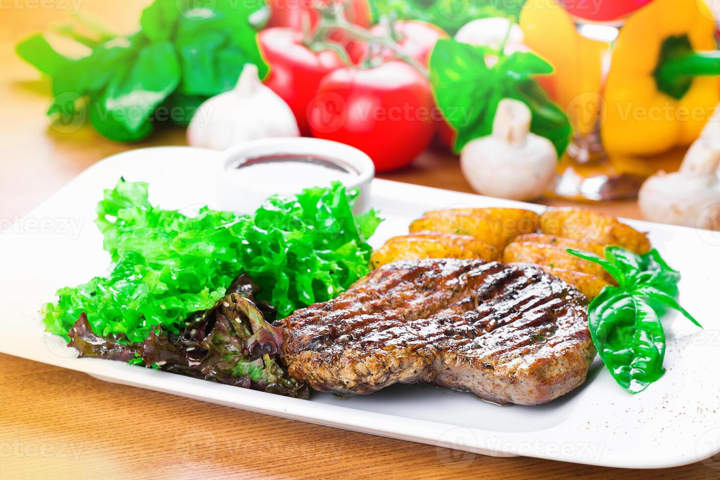 Delicious grilled steak served with fresh lettuce and golden potatoes in a vibrant kitchen setting photo