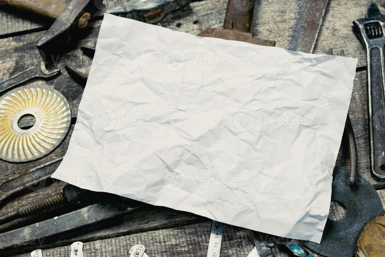 Crumpled paper placed on a workbench surrounded by various hand tools and hardware in a workshop setting photo