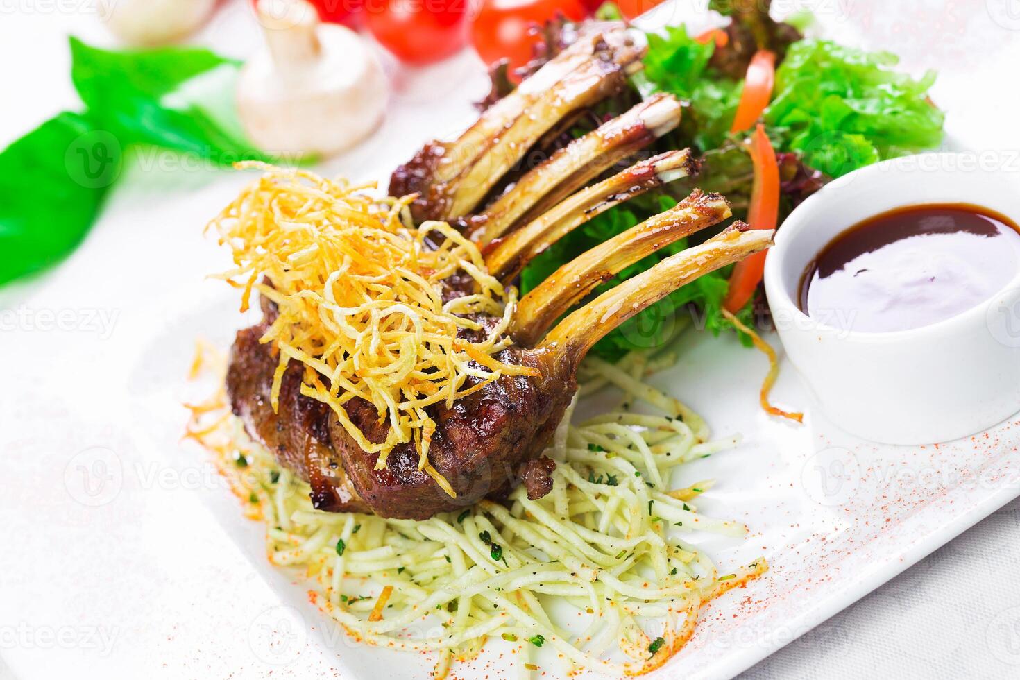 Luxurious plated lamb chop dish garnished with crispy noodles and fresh vegetables in a restaurant setting photo