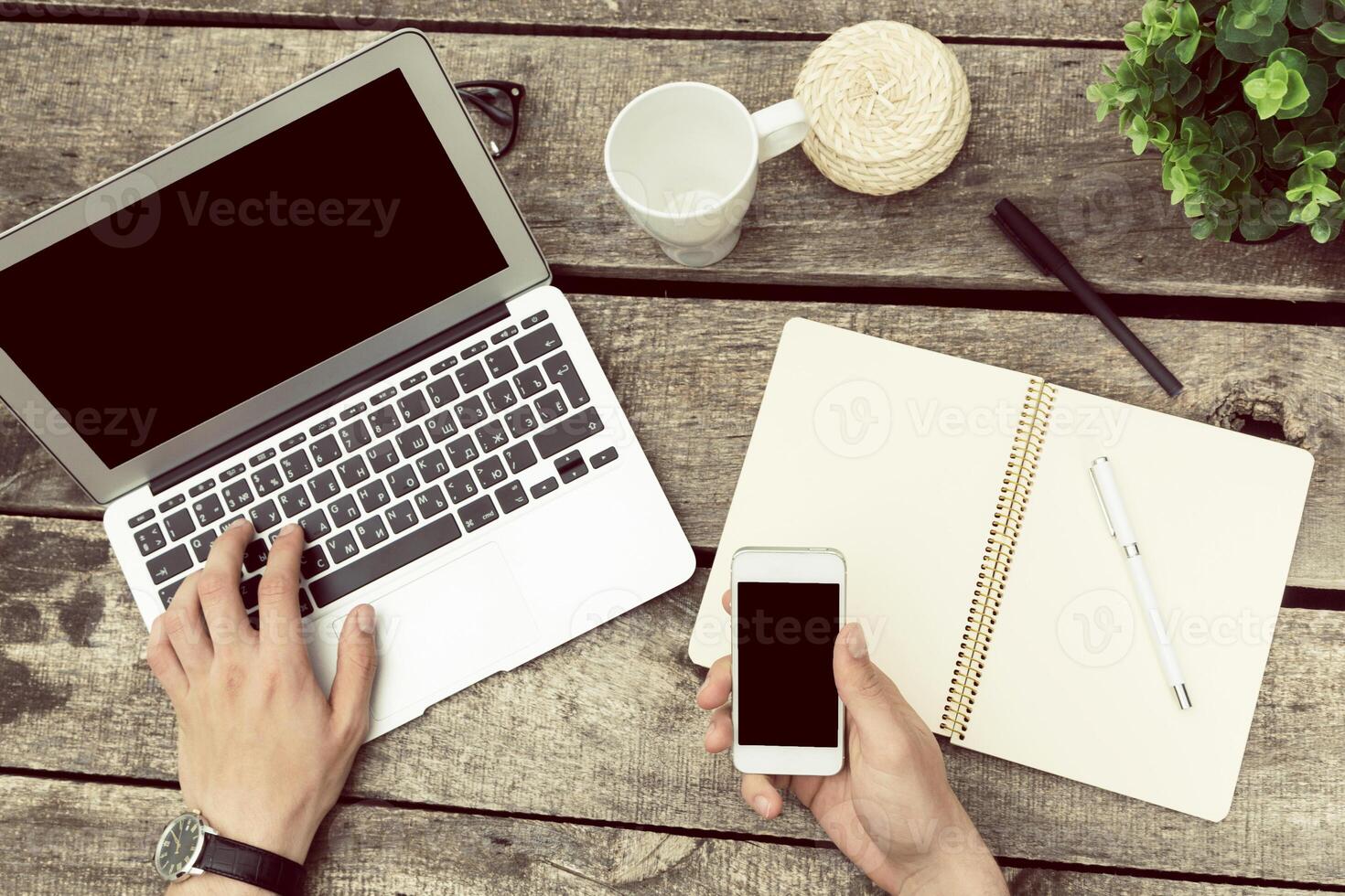 Working remotely on a wooden table with laptop, notebook, and smartphone during a productive afternoon photo