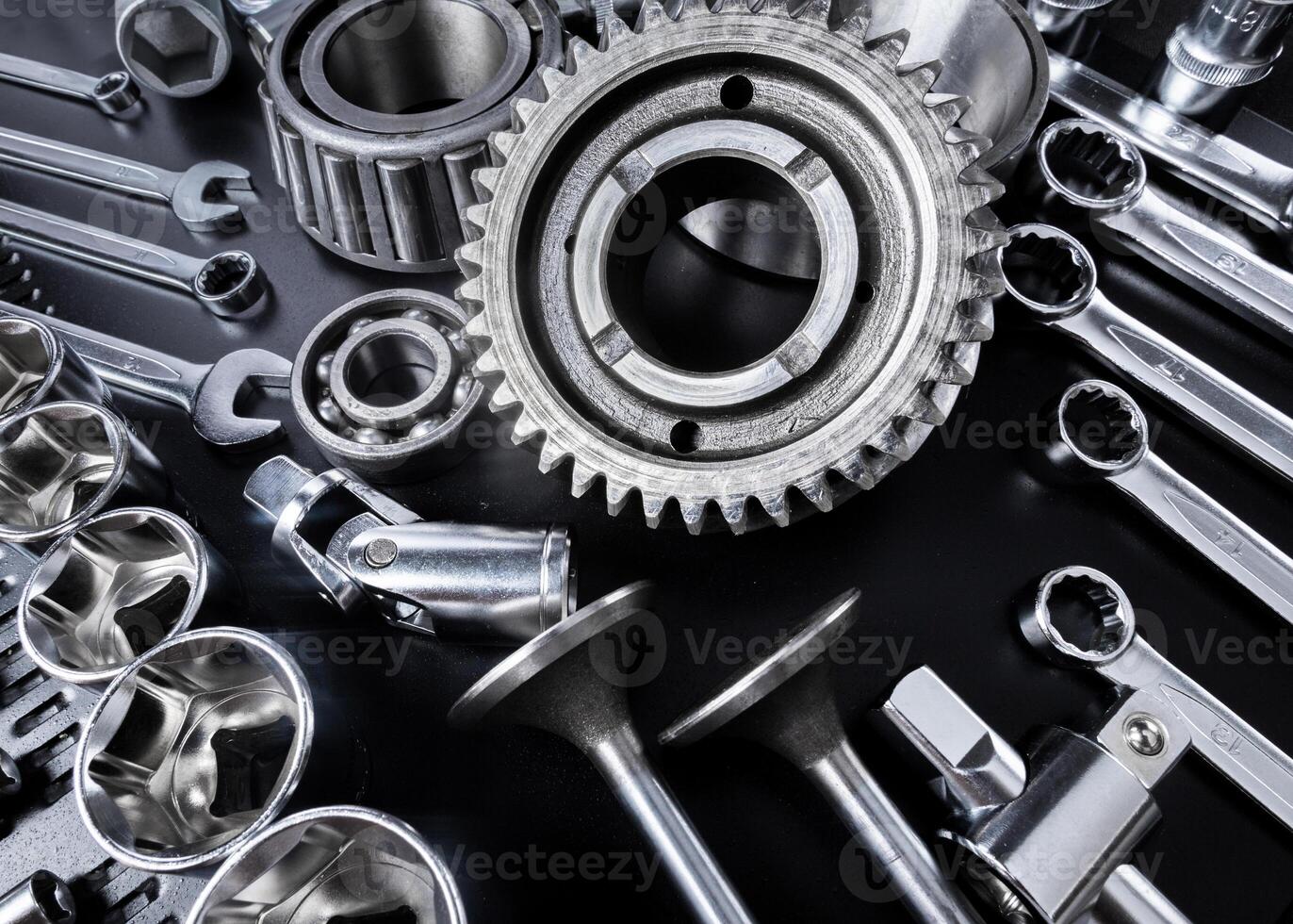 Assembly of metallic tools and parts laid out on a black surface for mechanical work photo