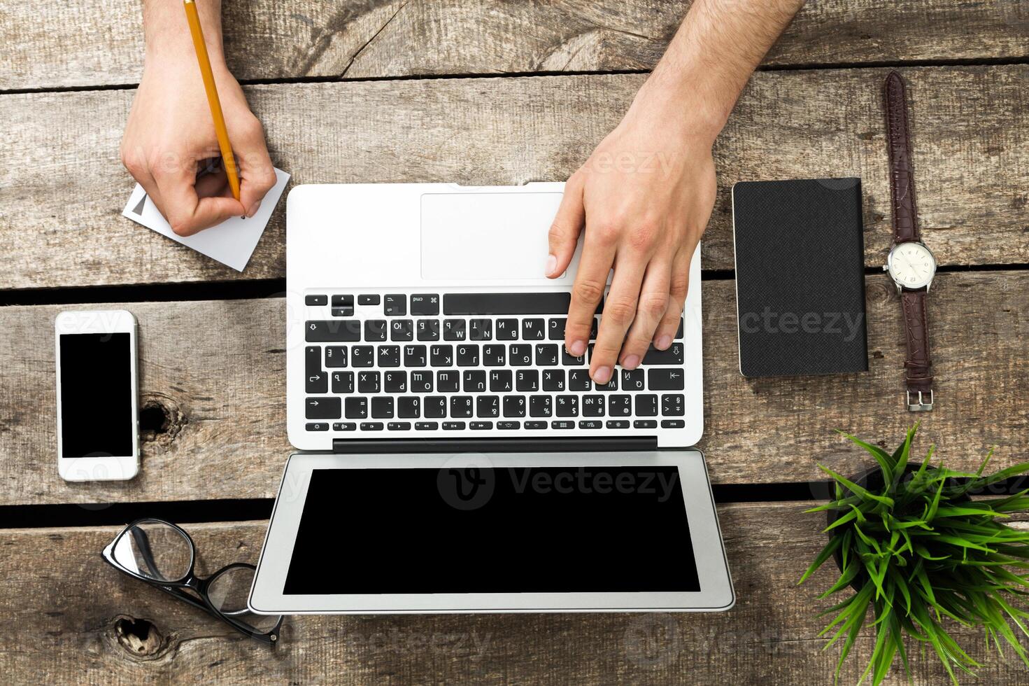 Workspace setup with laptop, smartphone, and stationery on wooden table during a productive day photo