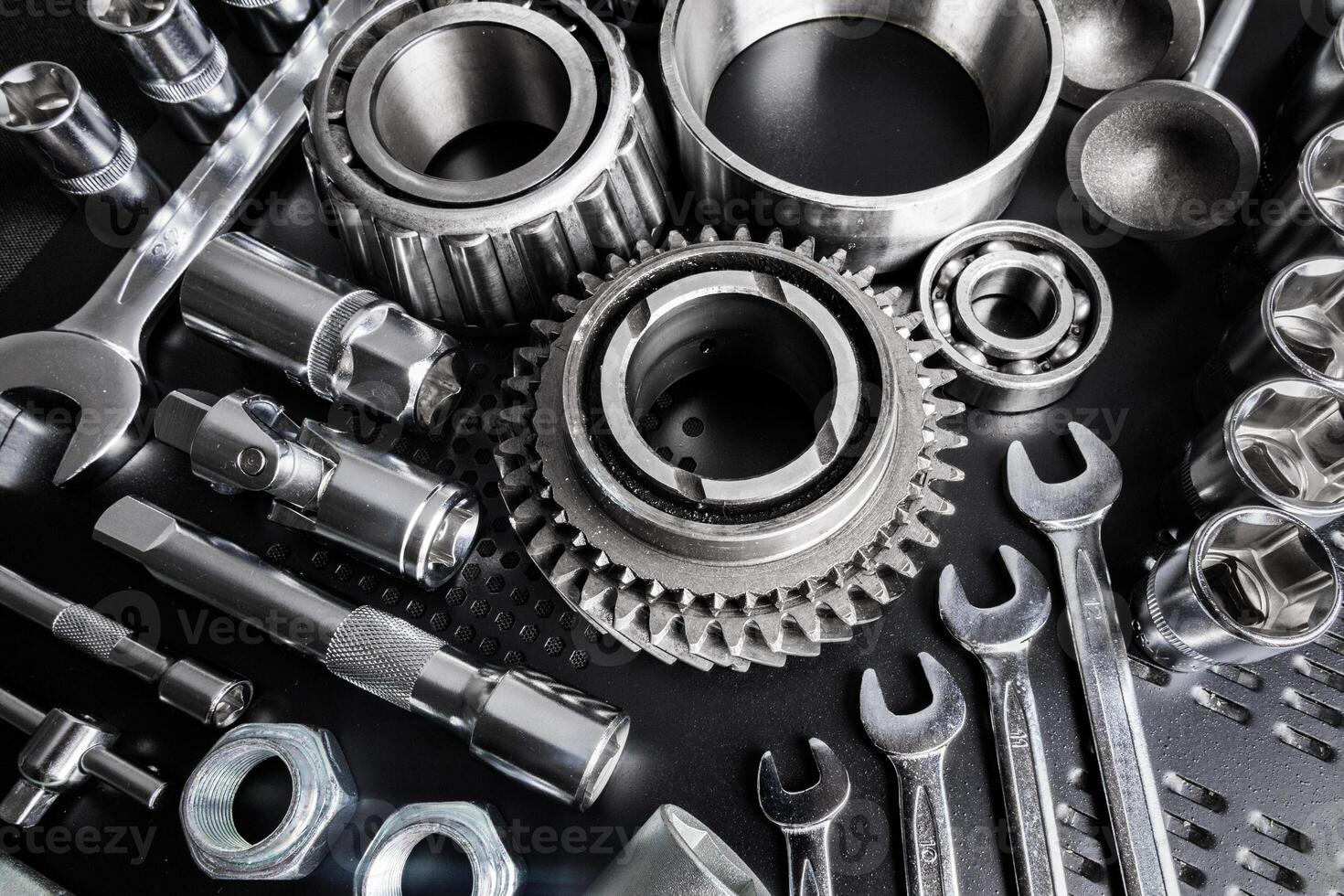 Various metallic tools and mechanical components arranged neatly on a black surface for mechanical work in a workshop setting photo