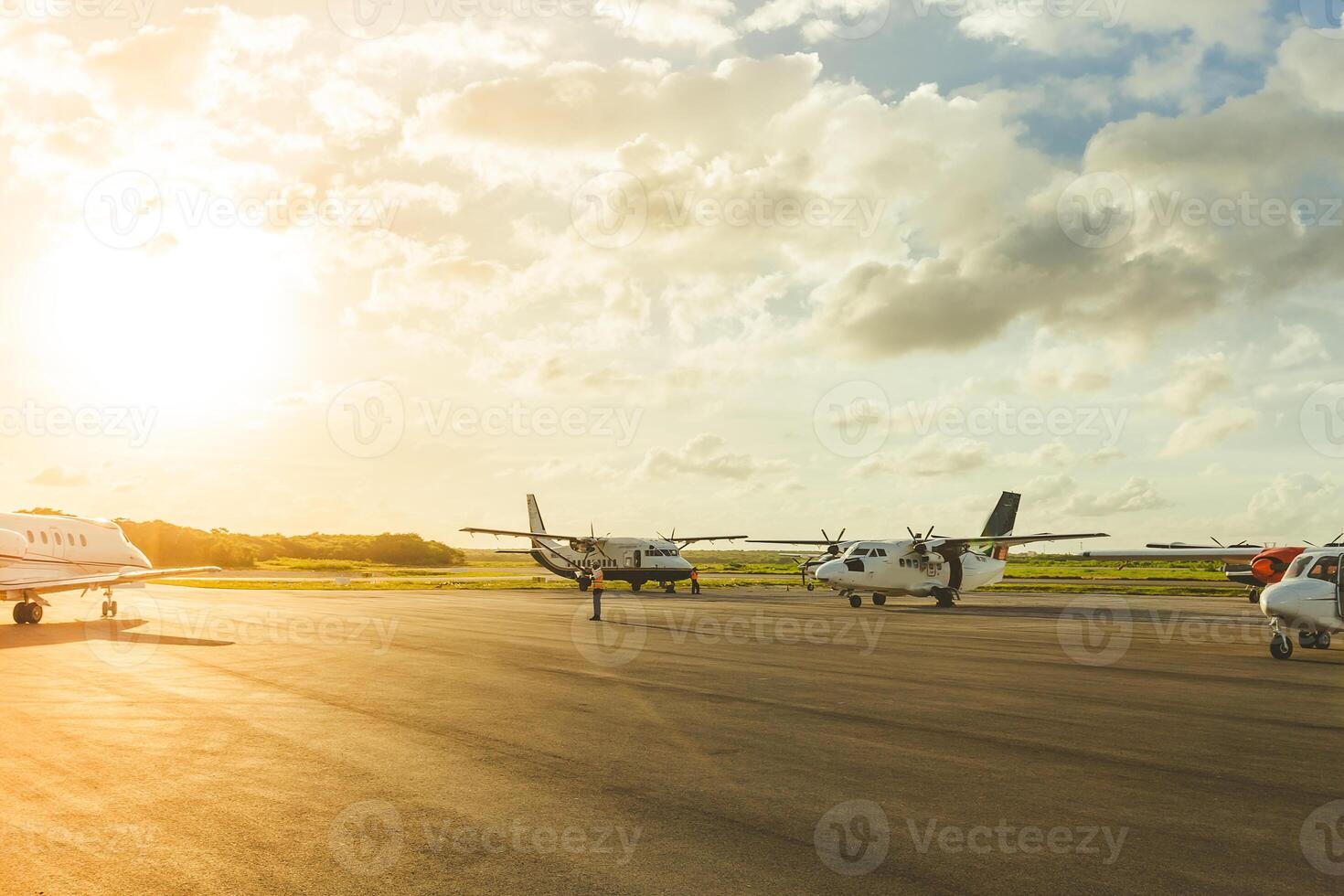 Planes parked on a runway during sunset at a small regional airport surrounded by vibrant clouds photo