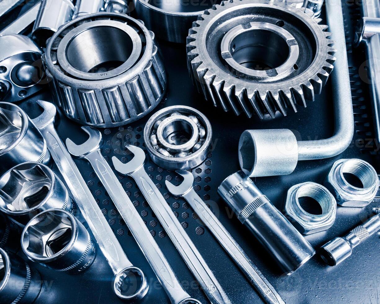 Collection of various metallic tools and components displayed on a workbench in a workshop setting photo