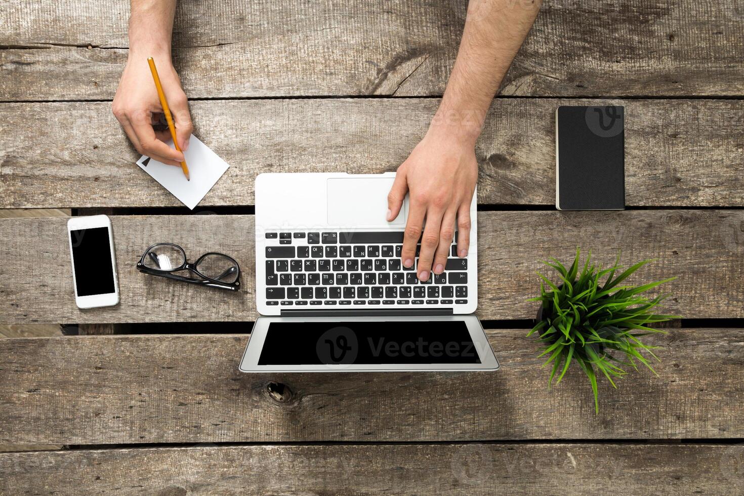 Working on a laptop at a wooden desk with stationery and personal items during a creative session photo