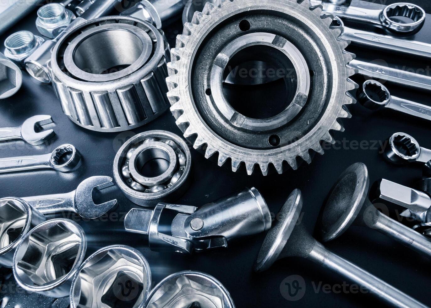 Various metallic tools and mechanical parts arranged on a dark surface for assembly and repair tasks photo