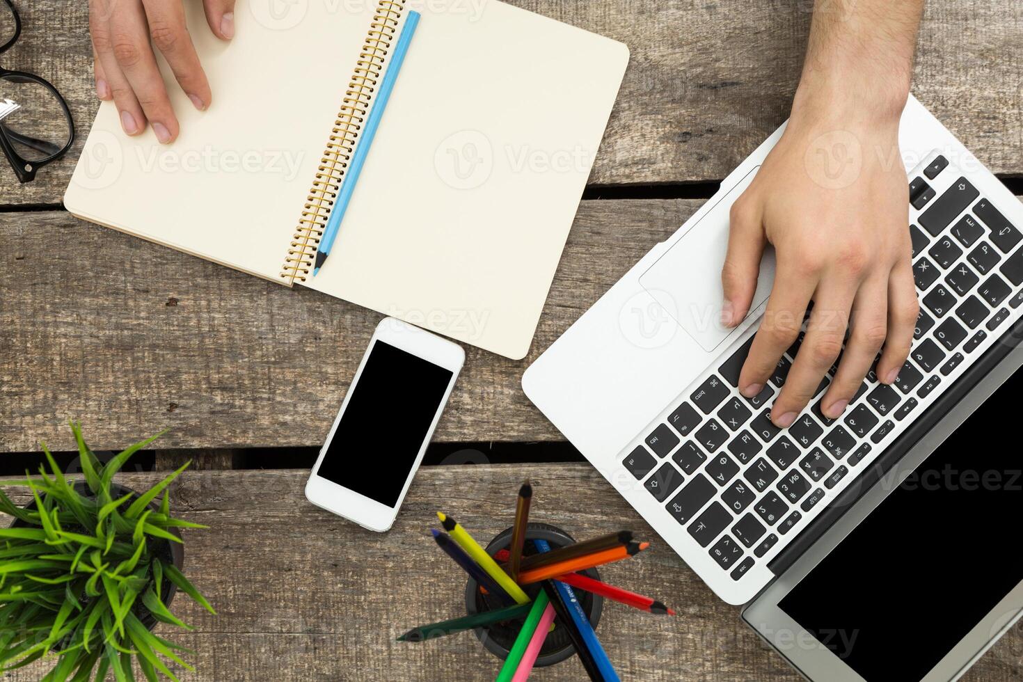 Working from home with a laptop, notepad, smartphone, and colorful pens on a wooden desk in a cozy environment photo