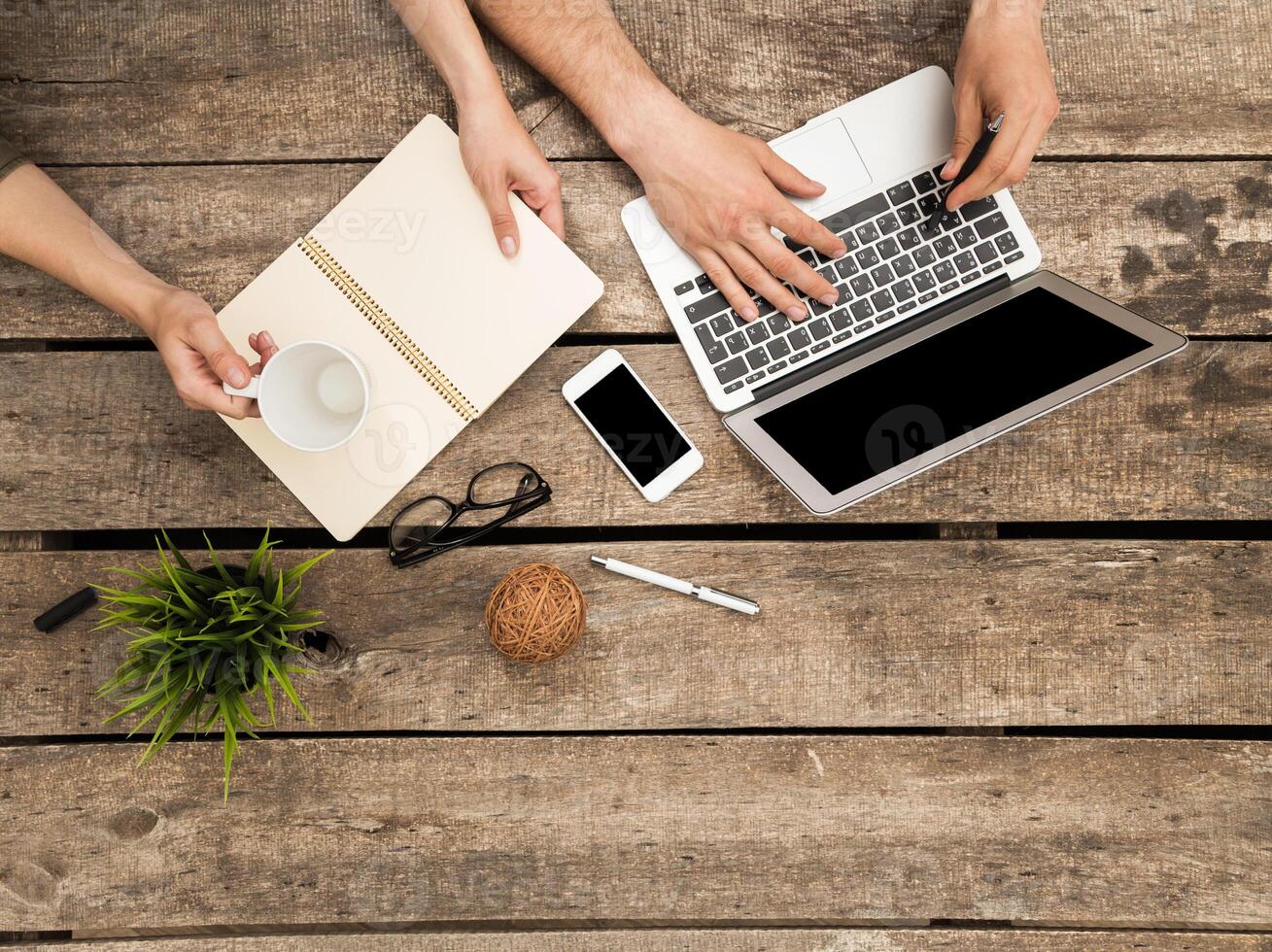 Collaborative workspace with coffee, laptop, and notes on a wooden table photo