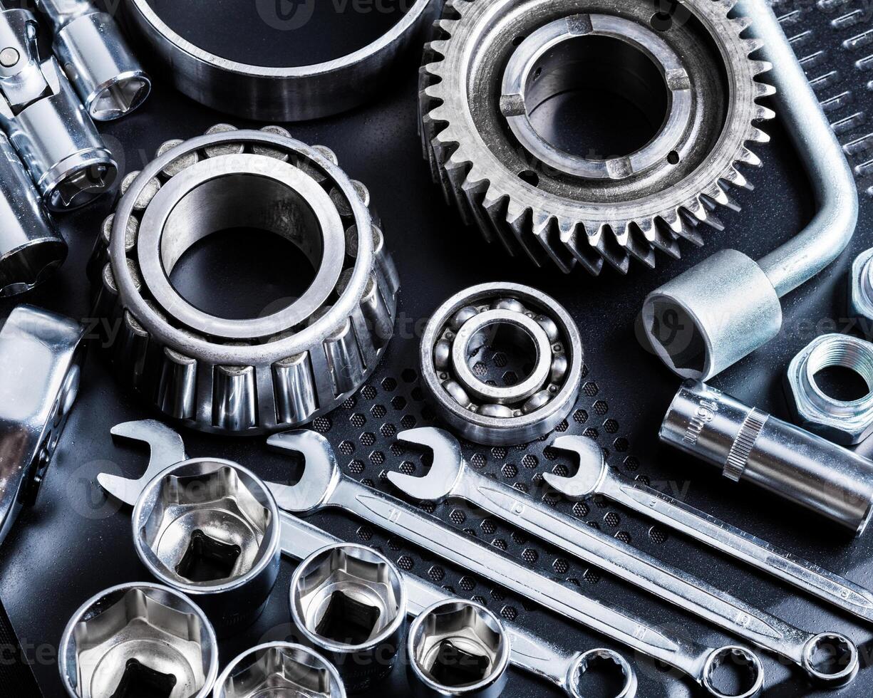 Collection of metallic tools and components arranged on a dark surface for mechanical work or engineering purposes photo