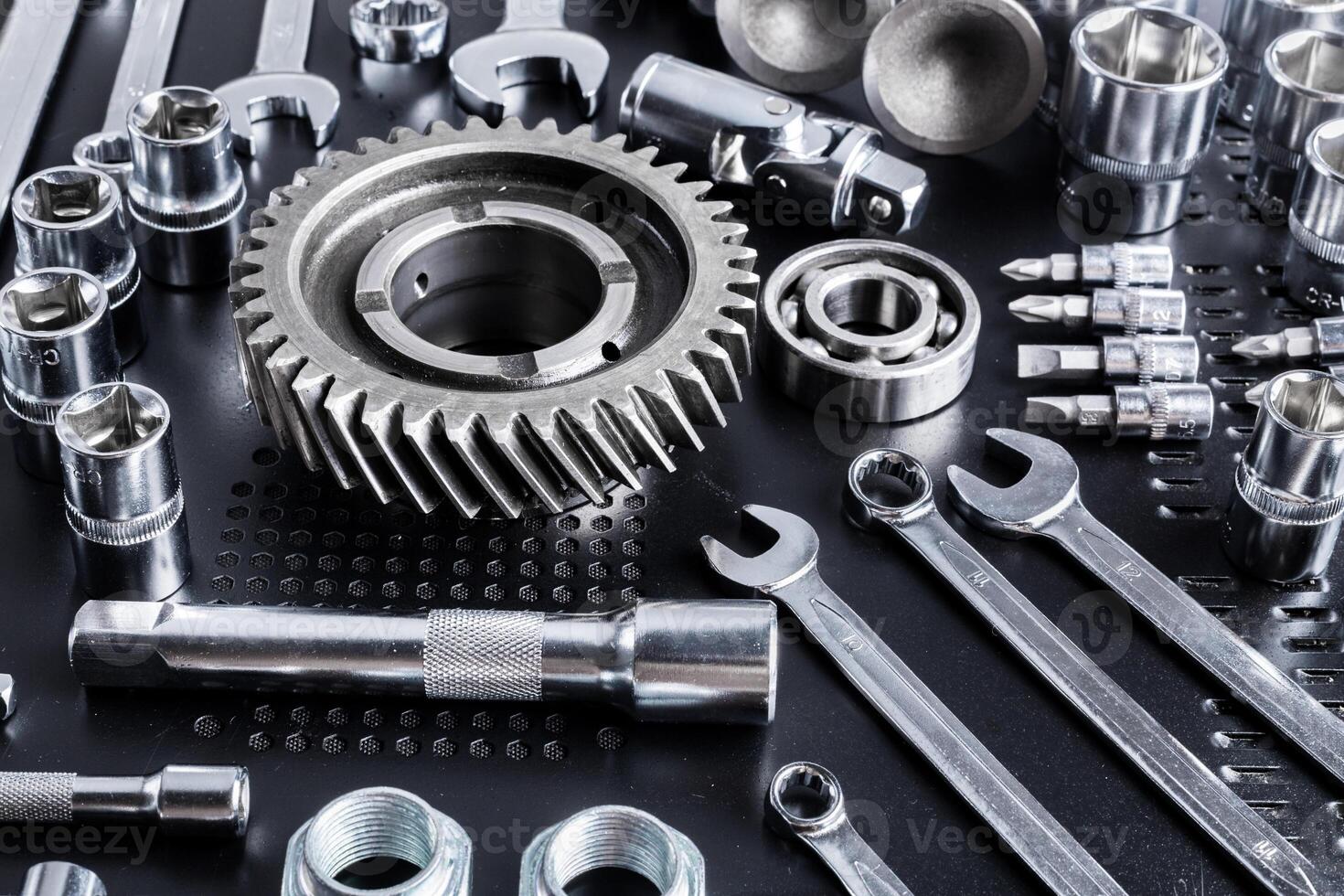 Collection of various metal tools arranged neatly on a black surface in a workshop for mechanical tasks photo
