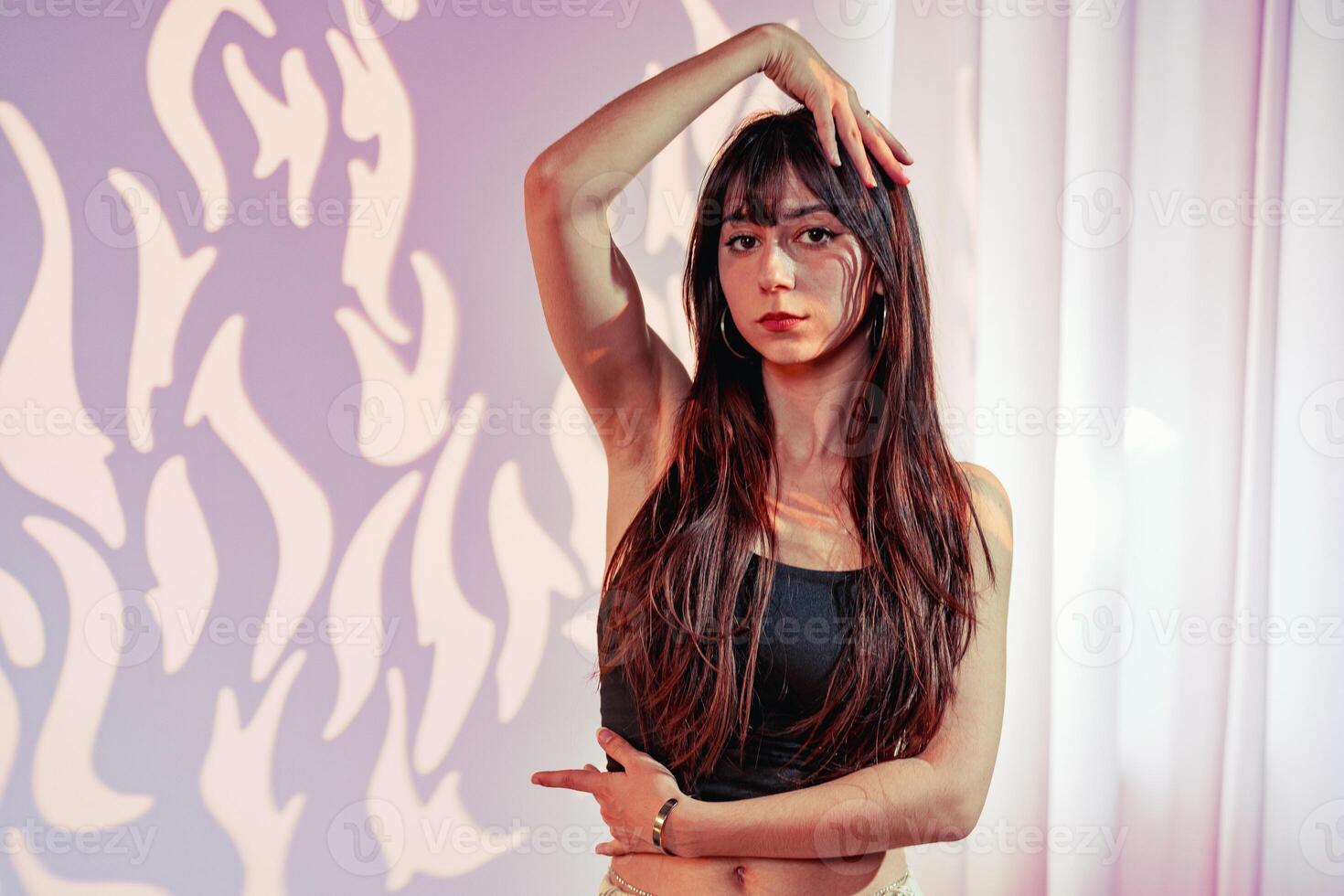 Model poses elegantly in a stylish studio with creative lighting and artistic backdrop photo