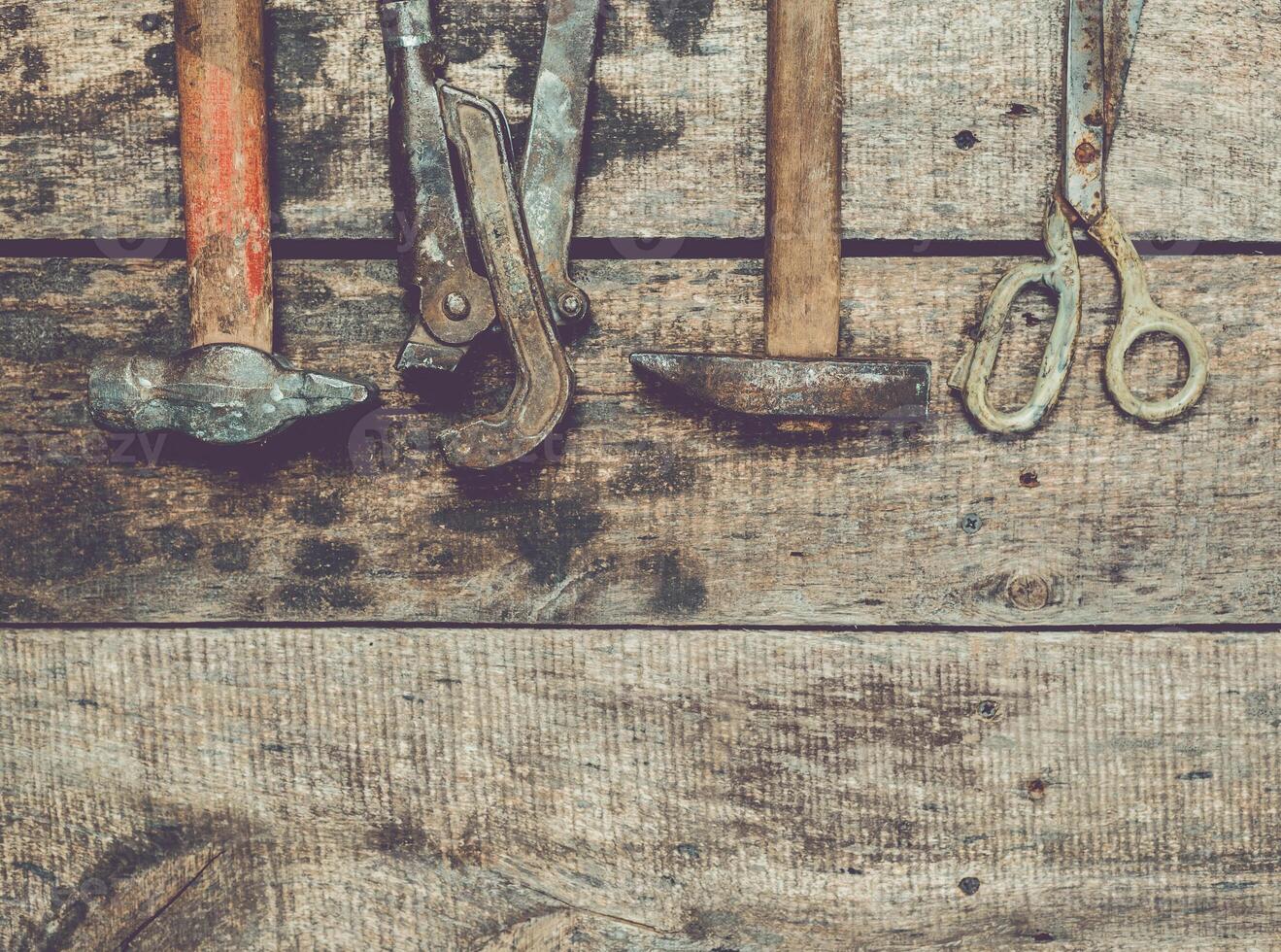 Tools arranged on a rustic wooden surface displaying various hand tools used for repair and construction work photo