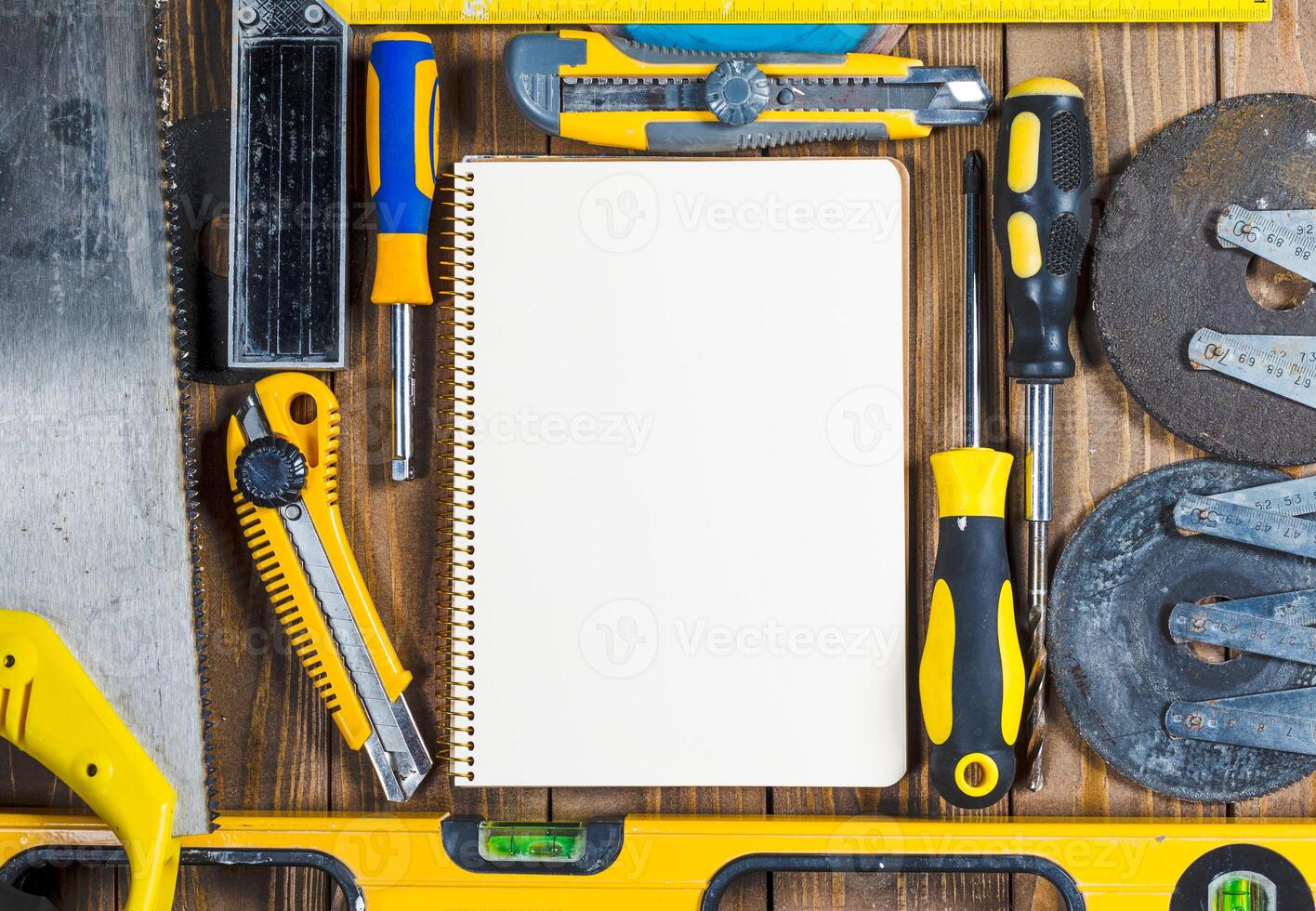 Tools and blank notepad arranged on a wooden surface in a workshop setting photo