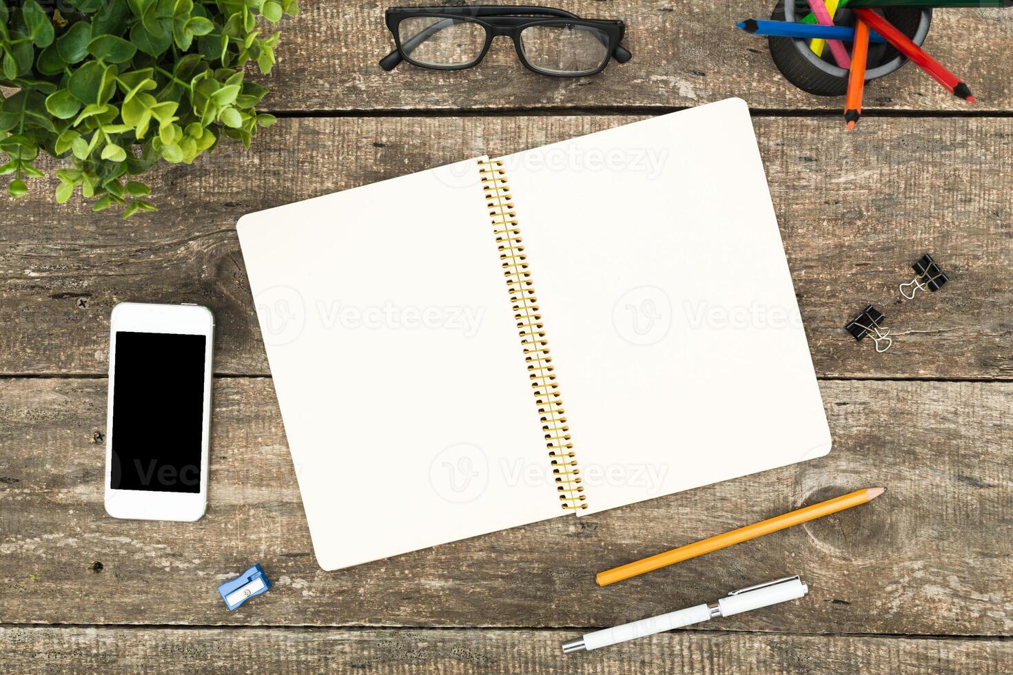 Workspace on a wooden table featuring a blank notebook, smartphone, and stationery items for creative brainstorming photo