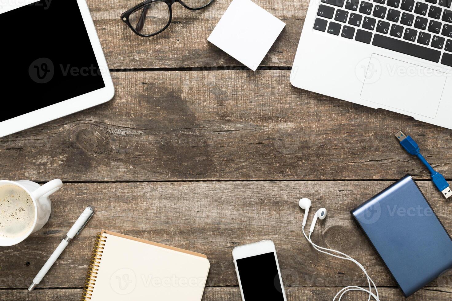 Workspace setup with electronics and stationary on rustic wooden table during daytime photo