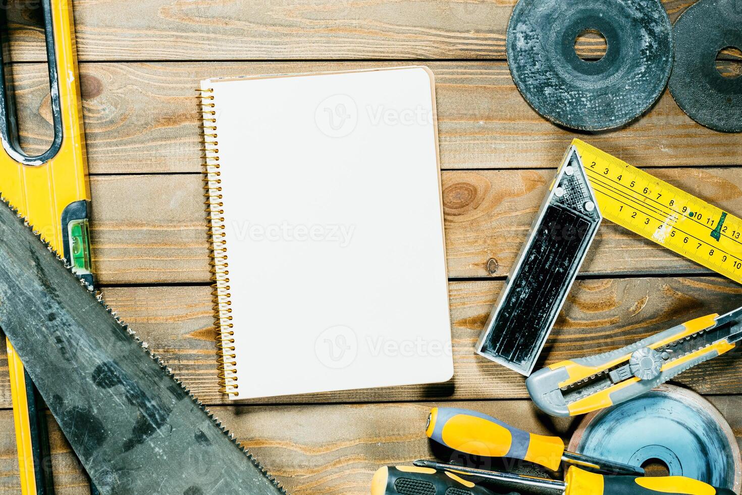 Workshop tools and a blank notebook arranged on a wooden surface for project planning photo