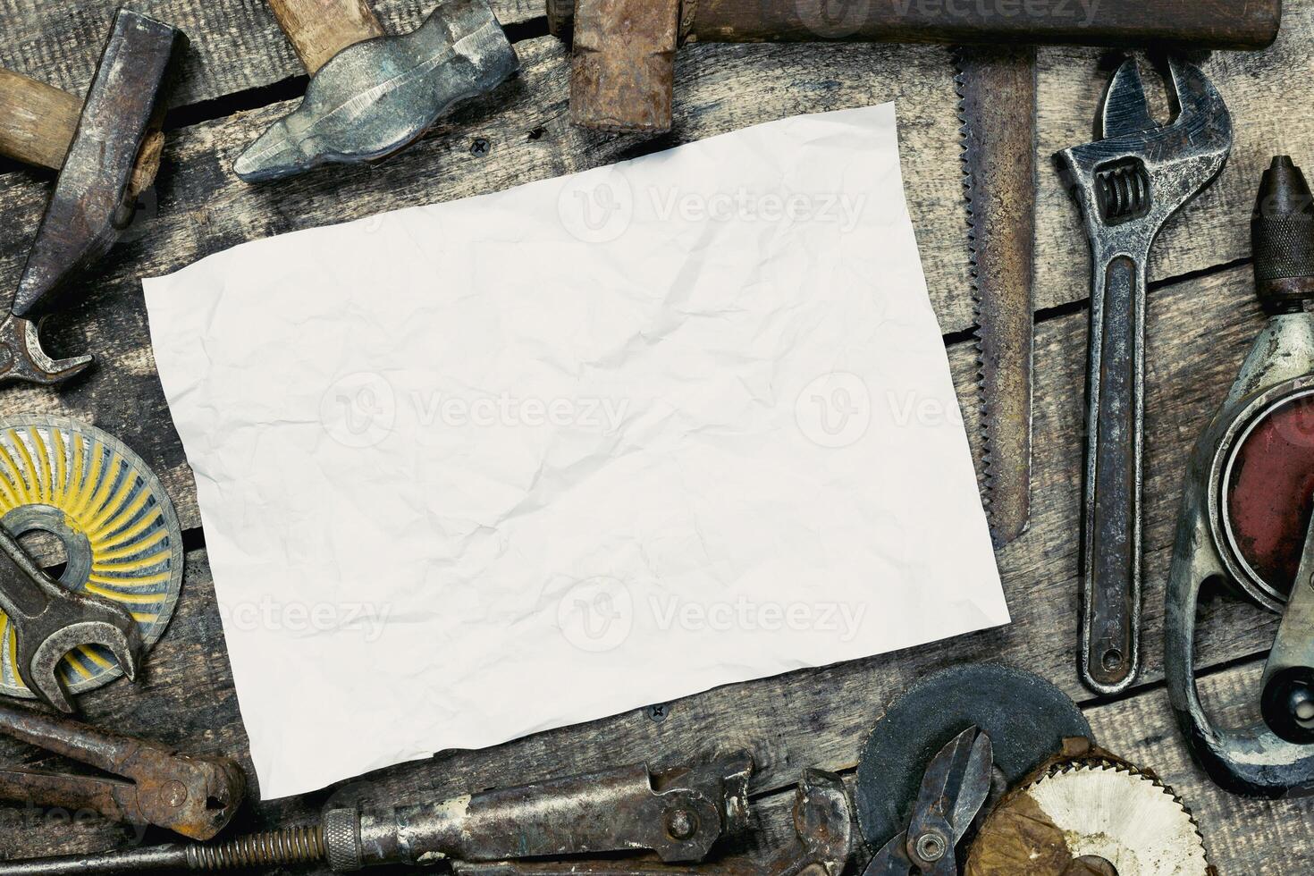 Tools arranged around a blank sheet of paper on a rustic wooden workspace for creative projects or planning sessions photo