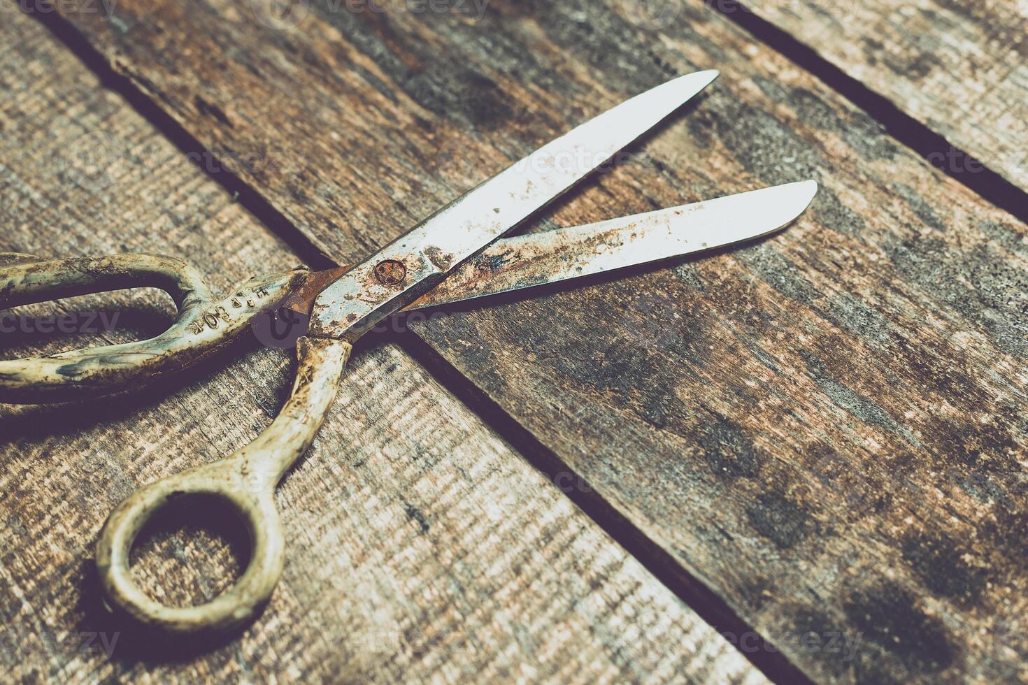 Old scissors resting on a rustic wooden table, showcasing weathered metal and vintage charm in a cozy workspace photo