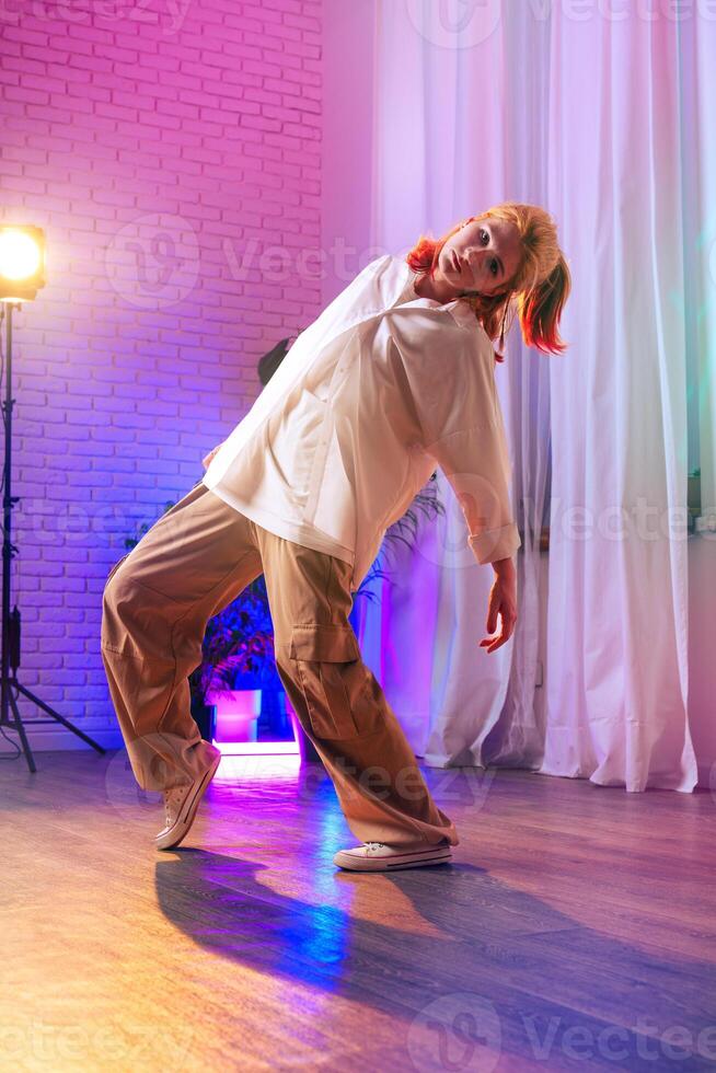 Energetic dancer performing contemporary moves in a vibrant studio during evening practice session photo