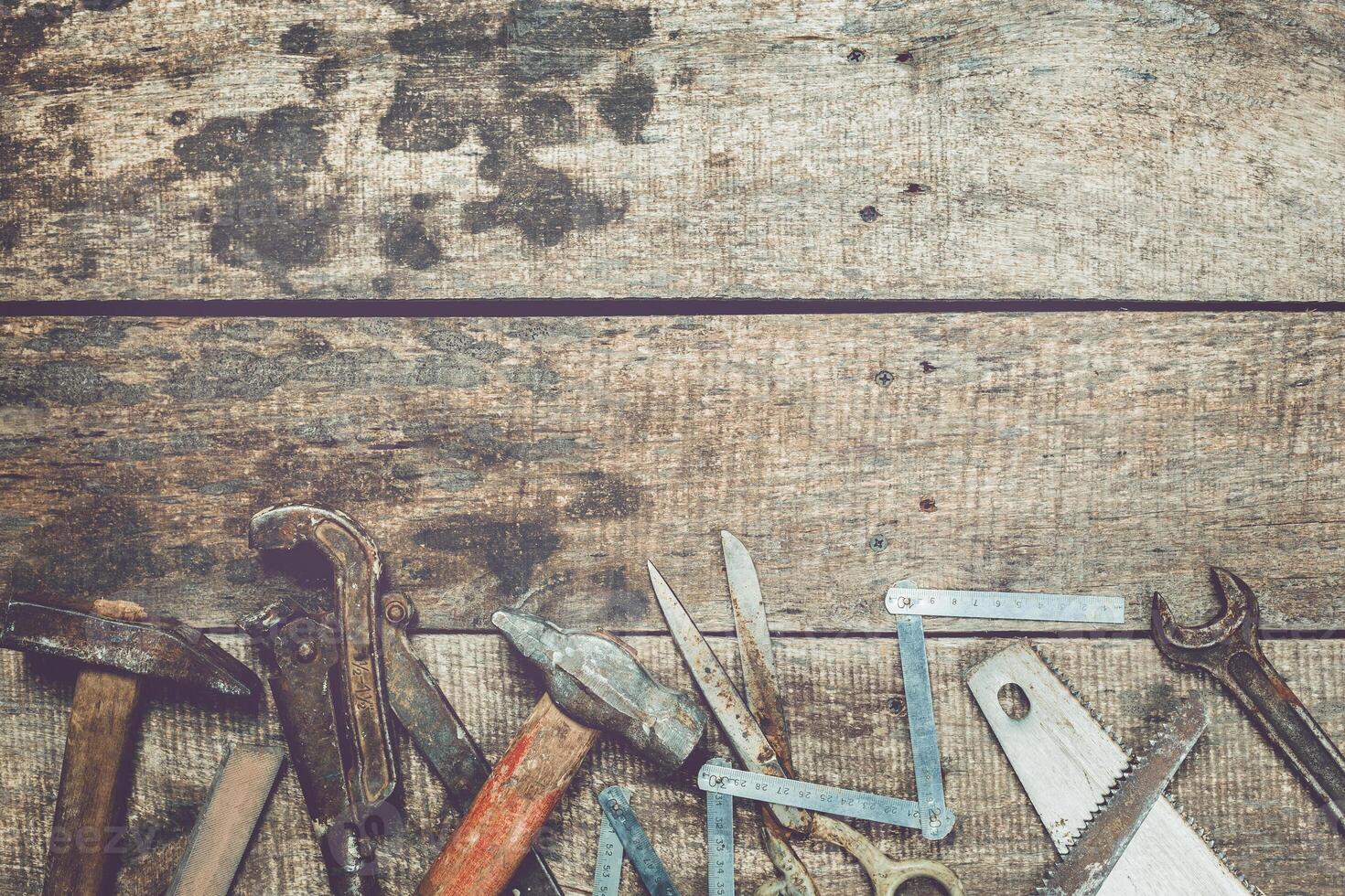 Collection of various hand tools arranged on a rustic wooden workbench in a workshop setting photo