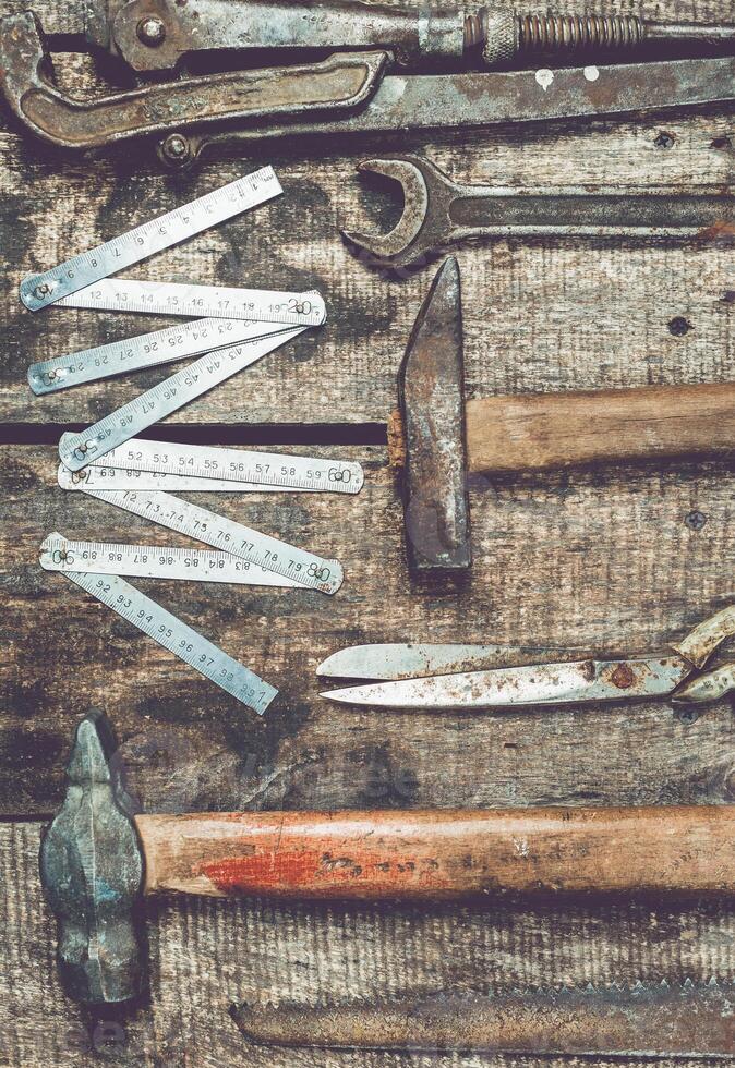 Collection of vintage tools arranged on a rustic wooden surface showcasing craftsmanship and history in an indoor workshop setting photo