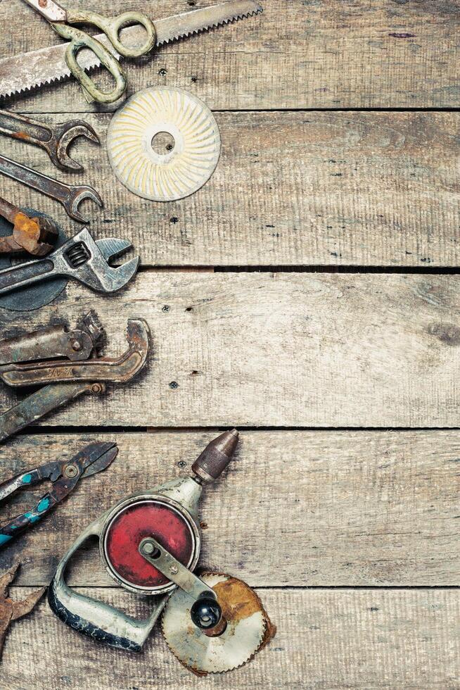 Collection of assorted hand tools arranged on a rustic wooden surface in a workshop setting during daylight photo