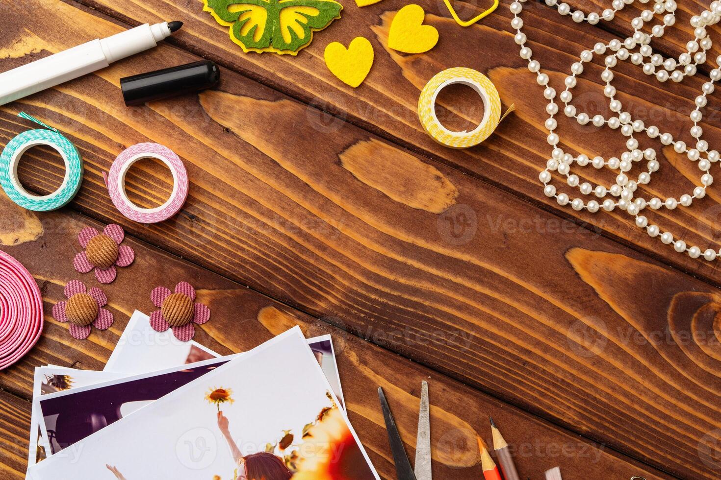 Creative crafting workspace with colorful supplies and printed photographs arranged on wooden table photo