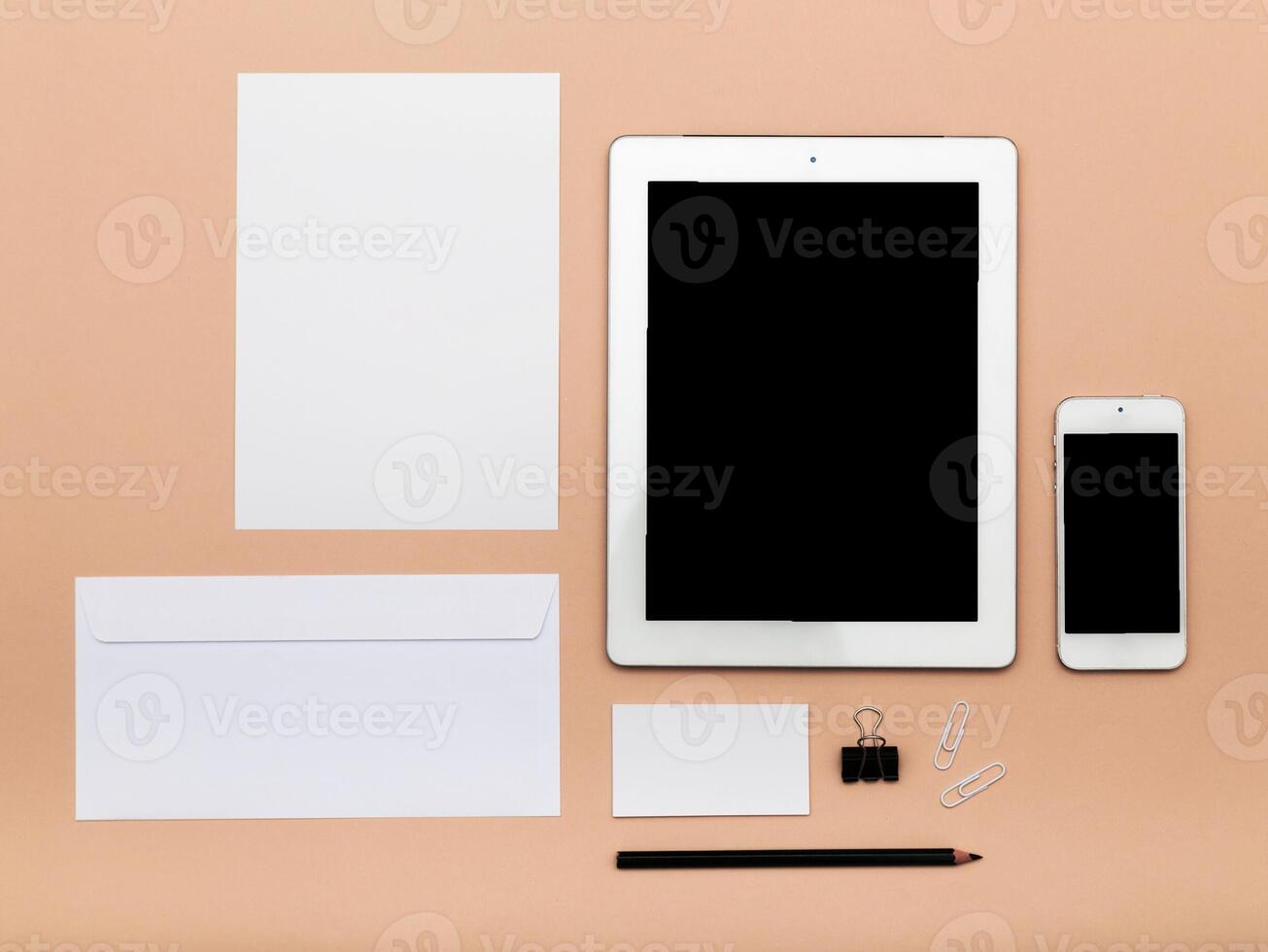Workspace arrangement with blank documents and digital devices on a neutral background photo