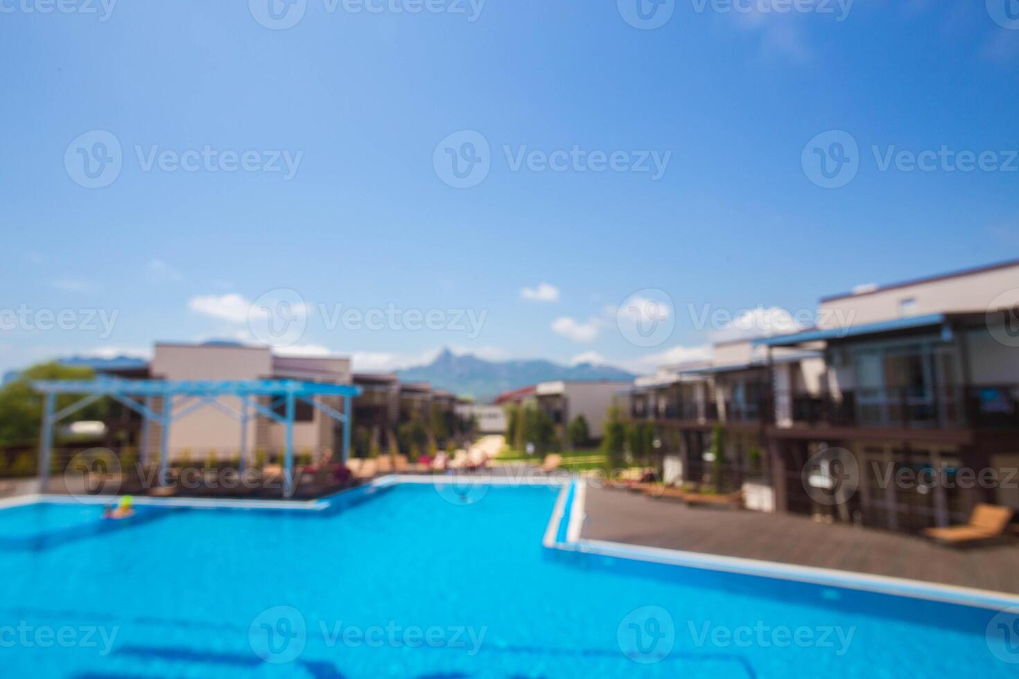 Scenic view of a resort pool area surrounded by modern buildings and mountains on a bright sunny day photo
