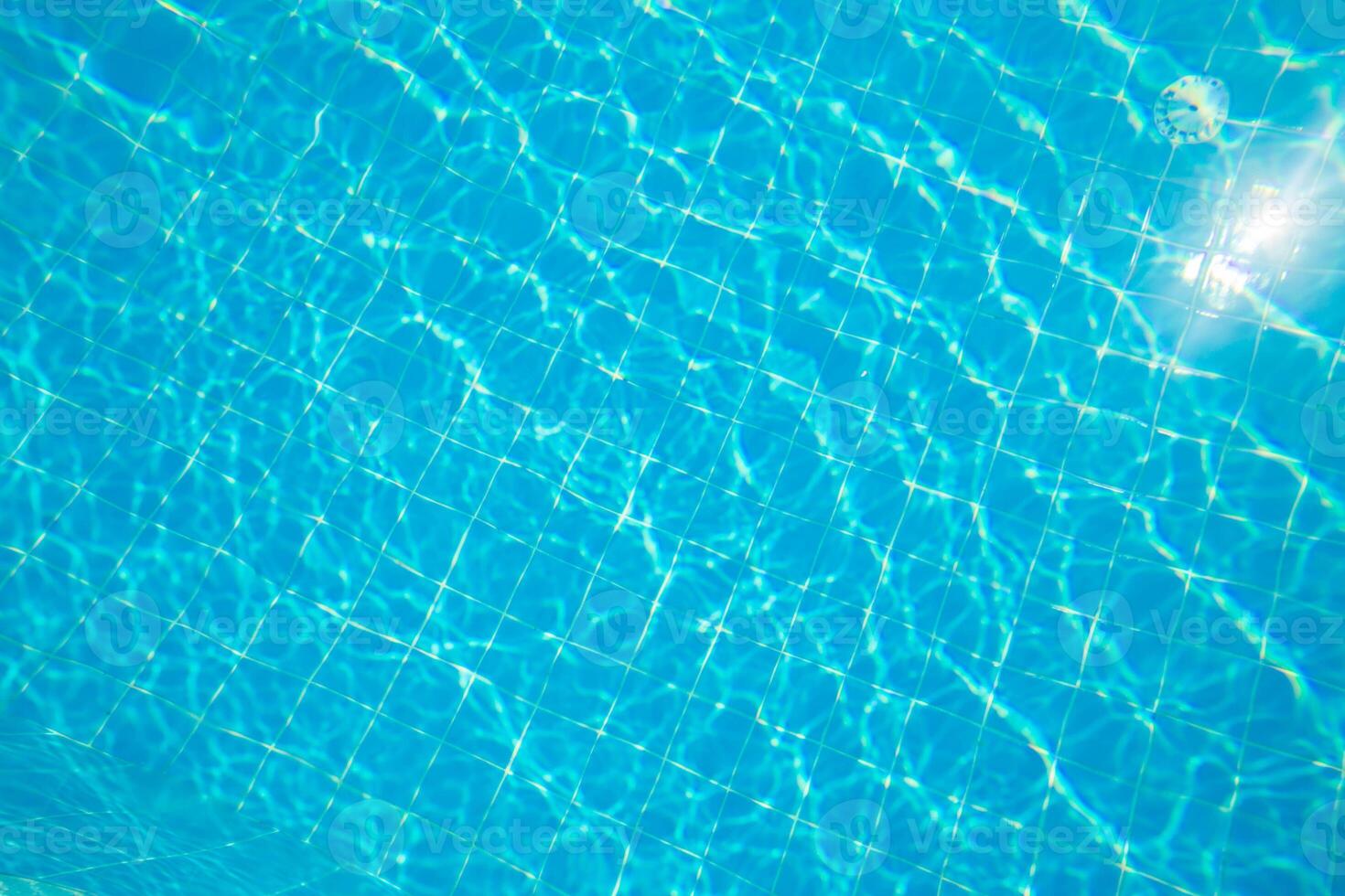 Clear water ripples create a serene atmosphere in a tiled pool under bright sunlight photo