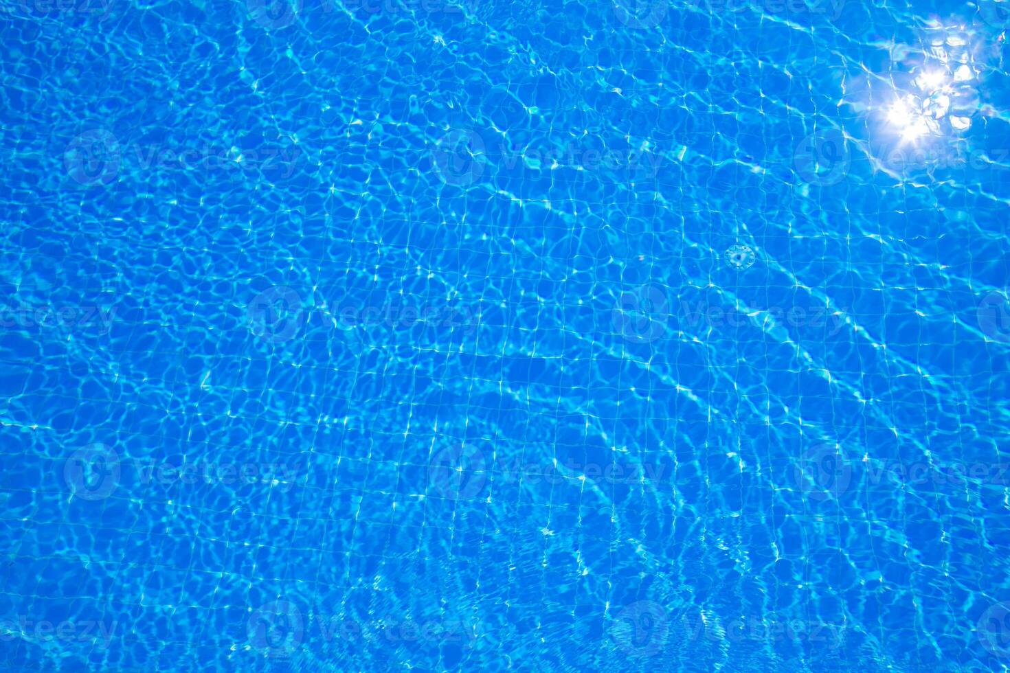 Crystal clear blue water ripples in a sunny pool during a bright summer afternoon in a perfect backyard setting photo