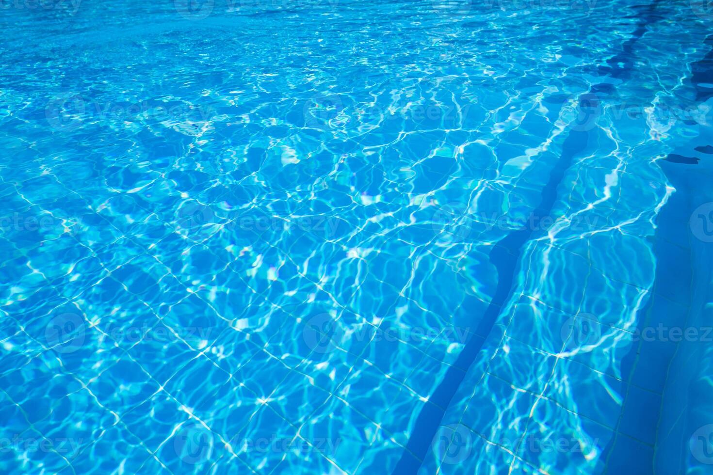 Sparkling turquoise water in a swimming pool on a sunny afternoon photo