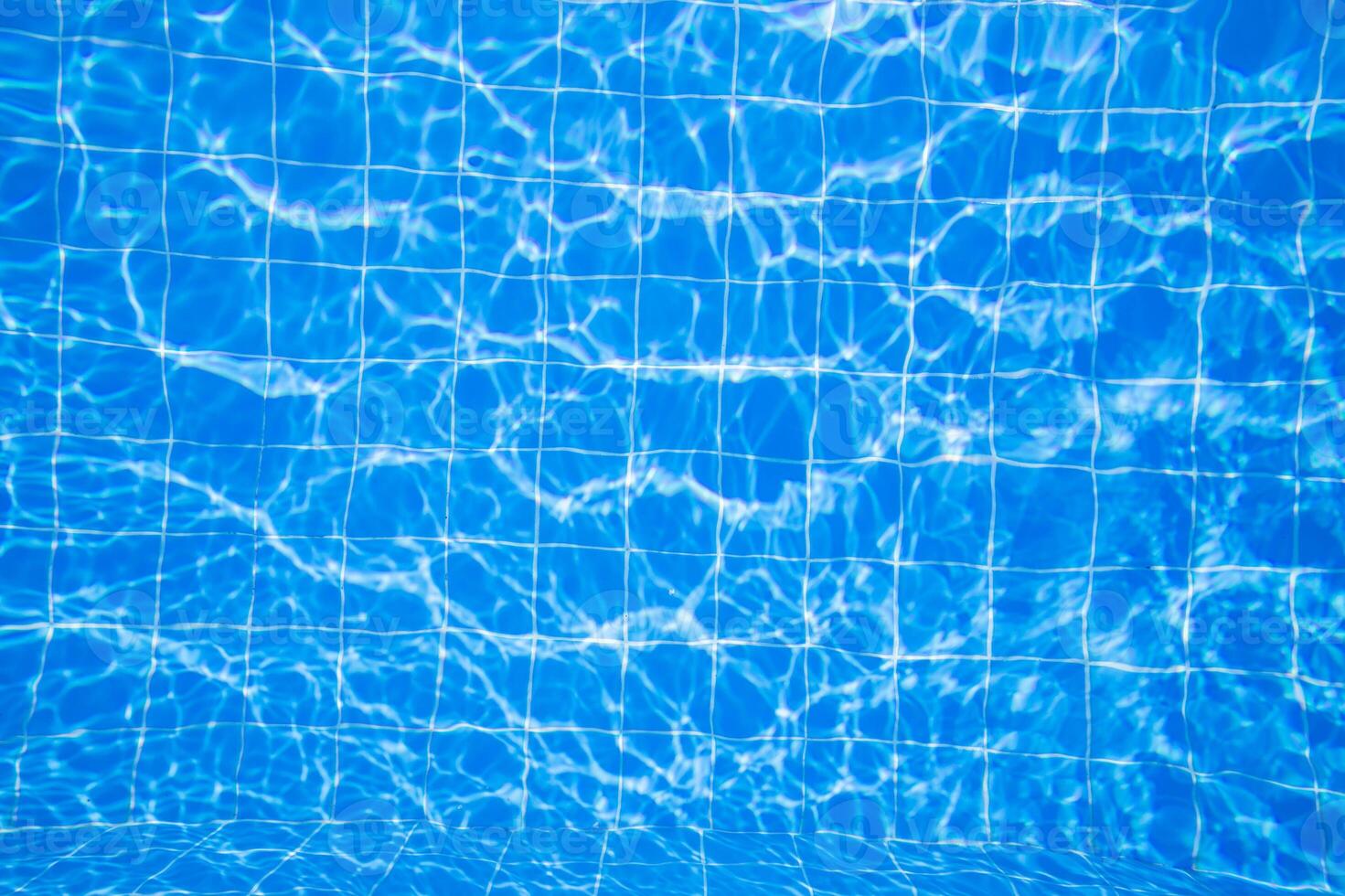 Water ripples create beautiful patterns on tiled pool surface under sunlight during a clear day photo