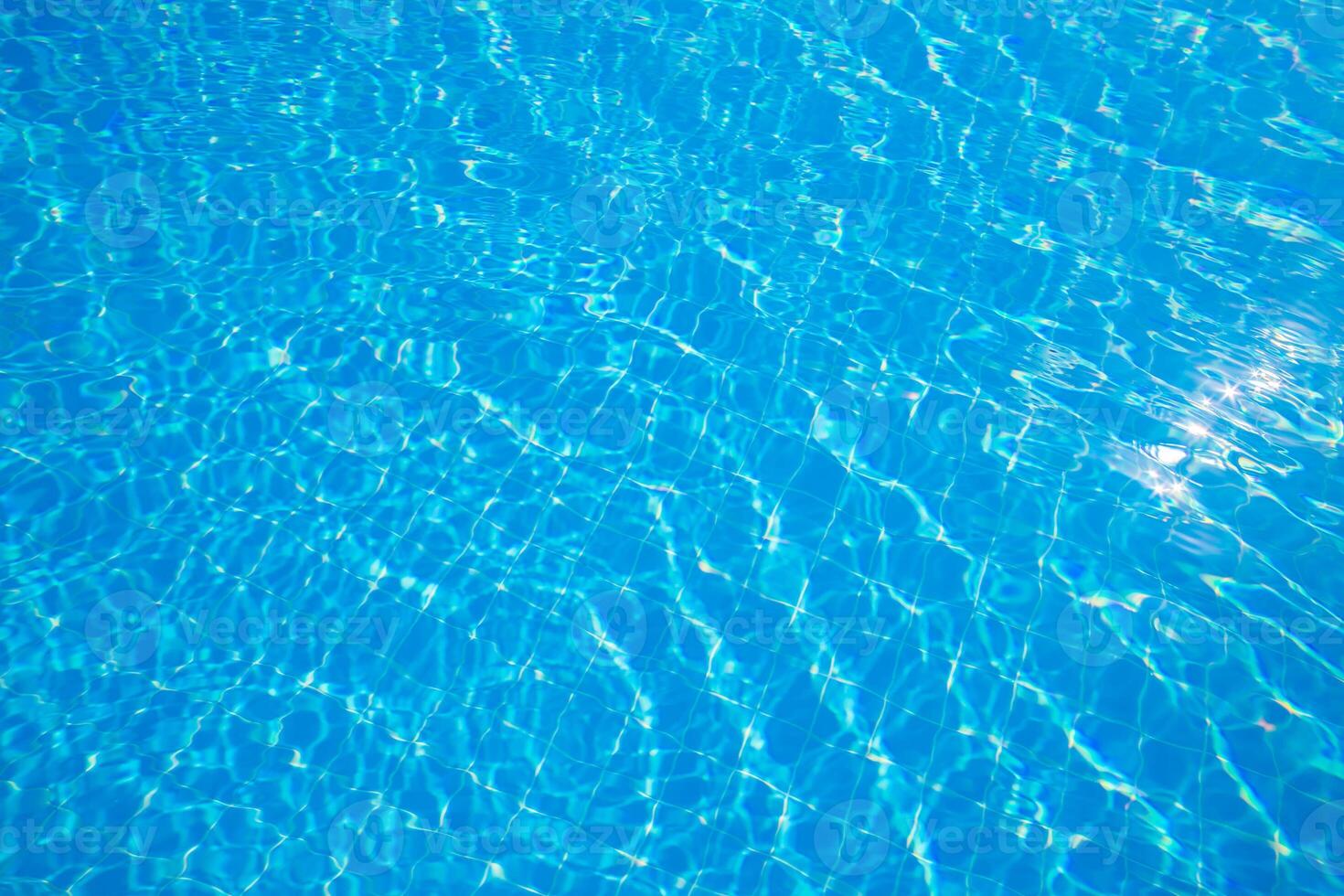 Bright sunlight illuminating clear blue water in a swimming pool during a warm summer afternoon photo