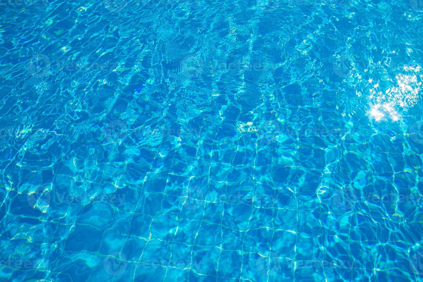 Crystal clear blue water reflecting sunlight in a serene swimming pool setting during the daytime photo