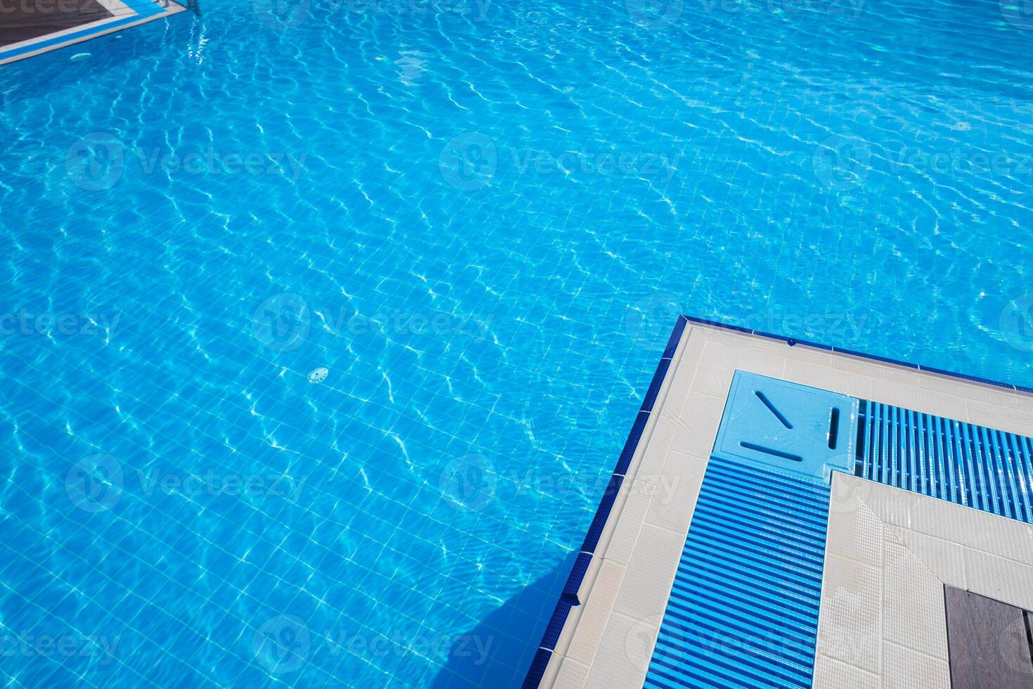 Bright blue pool water reflecting sunlight in a relaxing outdoor environment near lounge area photo
