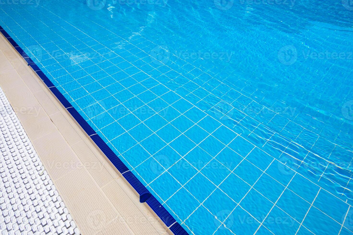 Bright blue swimming pool with tiled edges and sunlit water during a sunny day in a relaxing outdoor setting photo