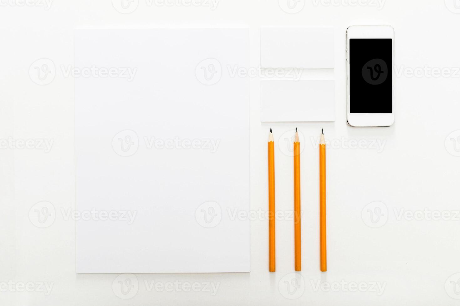 Workspace setup with white paper, orange pencils, and smartphone for creative projects and note-taking photo