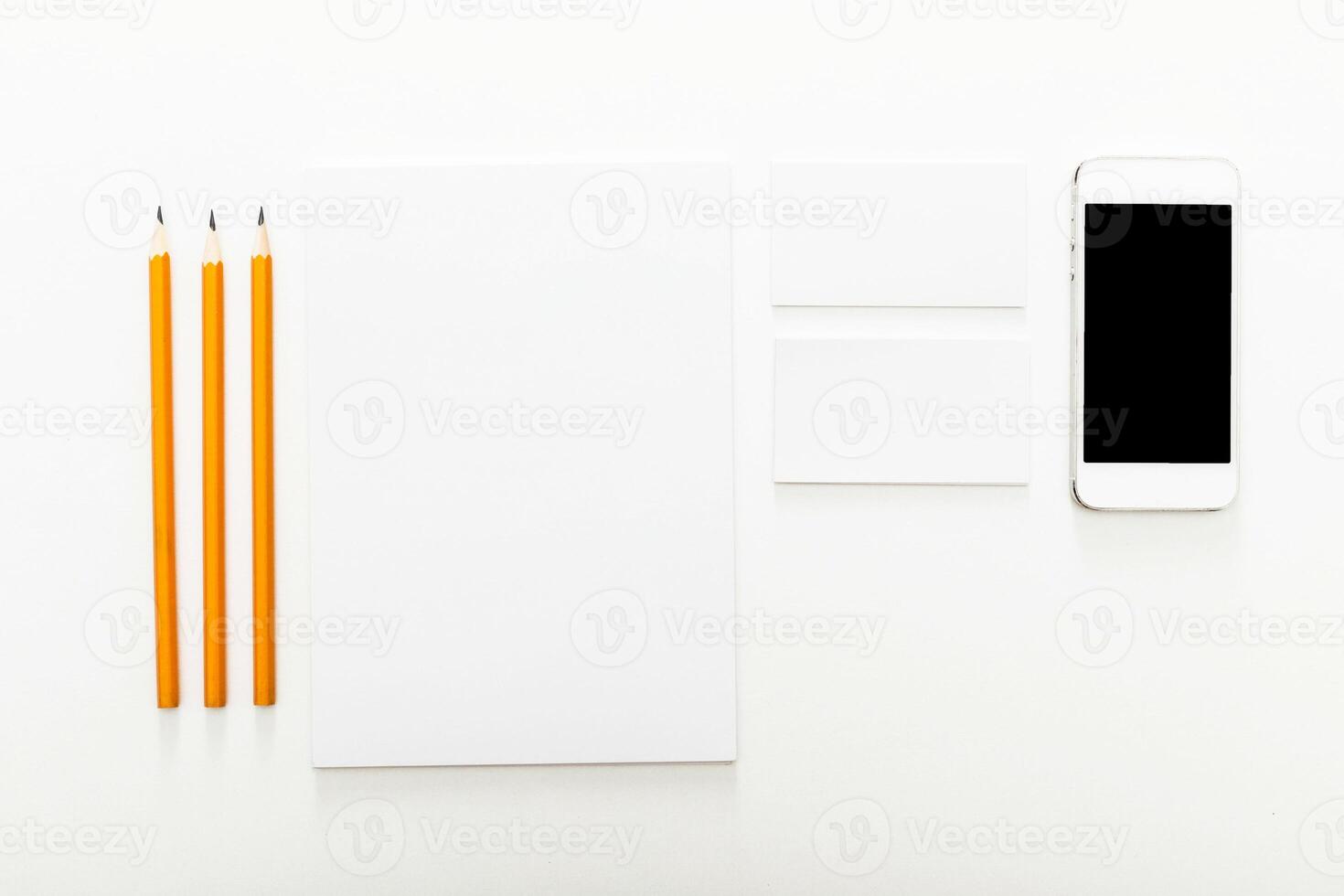 Workspace setup with pencils, blank notepad, business cards, and smartphone on clean surface photo