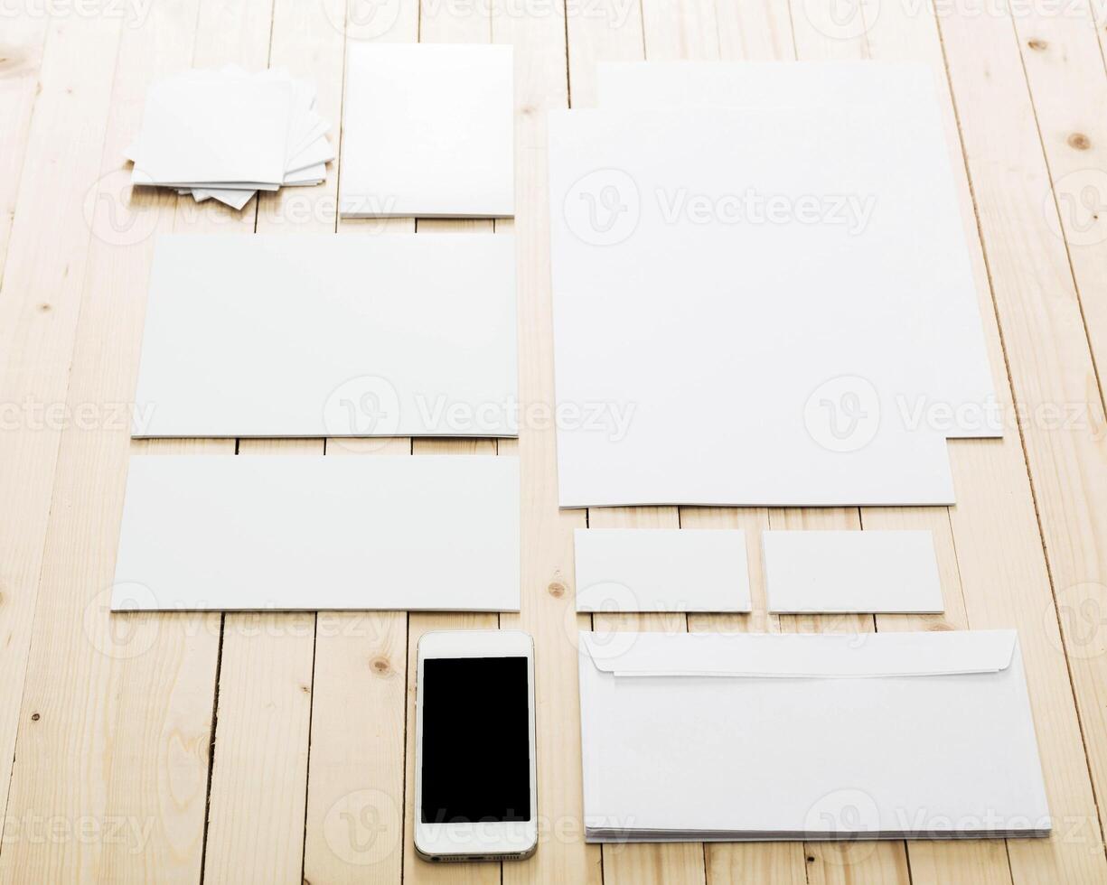 Collection of blank stationery items and a smartphone arranged on a wooden table photo