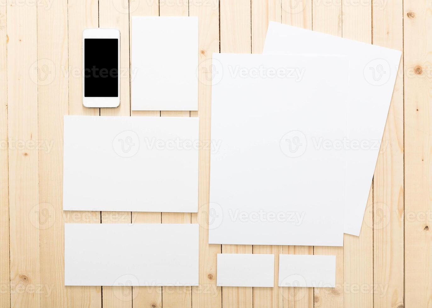 Blank stationery and smartphone arranged on wooden surface for creative workspace inspiration photo