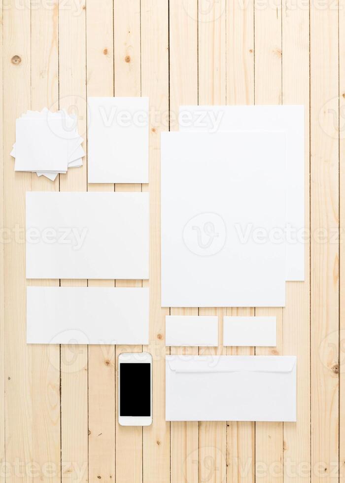 Blank stationery and smartphone arranged on wooden table for design or branding projects photo