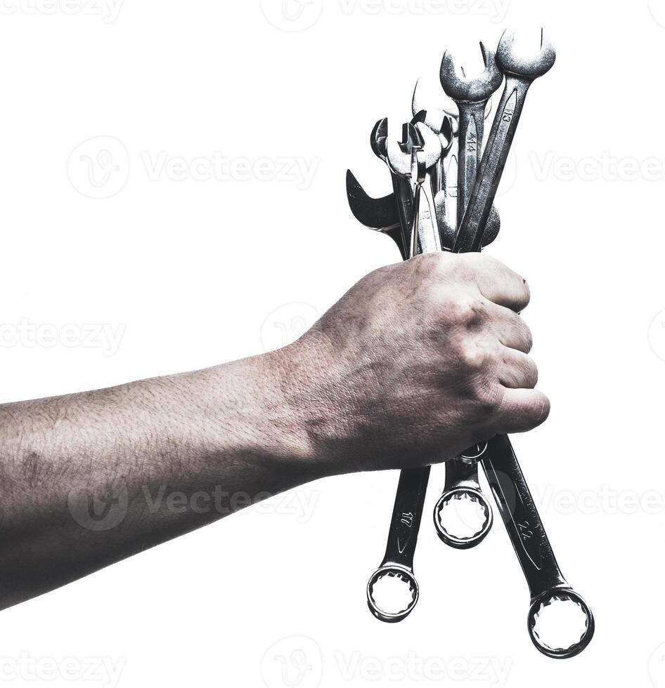 Hand gripping a set of shiny metal wrenches indicating readiness for mechanical work outdoors photo